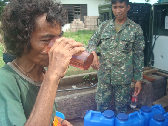 An elderly woman drinks a glass of purified water she received, July 14, from a Filipino Marine operating an Aspen 2000DM water purification system at a water distribution area in Culandanum, Palaw-an. The armed forces of the Philippines deployed a five-man team with the National Development Support Command to Palaw-an, June 23, for a humanitarian operation to provide aid and prevent the spread of a cholera outbreak.