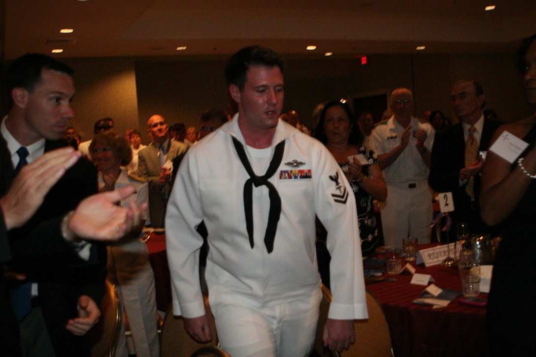 Petty Officer 2nd Class Jacob Emmott, a corpsman with 1st Battalion, 2nd Marine Regiment, 2nd Marine Division, is applauded by his family and fellow service members before being awarded the Silver Star Medal at the Third Annual Naval Safe Harbor Award Ceremony, in Washington D.C., July 14, 2011. Emmott was awarded the Silver Star, the third highest award for valor in the United States armed forces, for his actions in Helmand Province, Afghanistan, 2010.