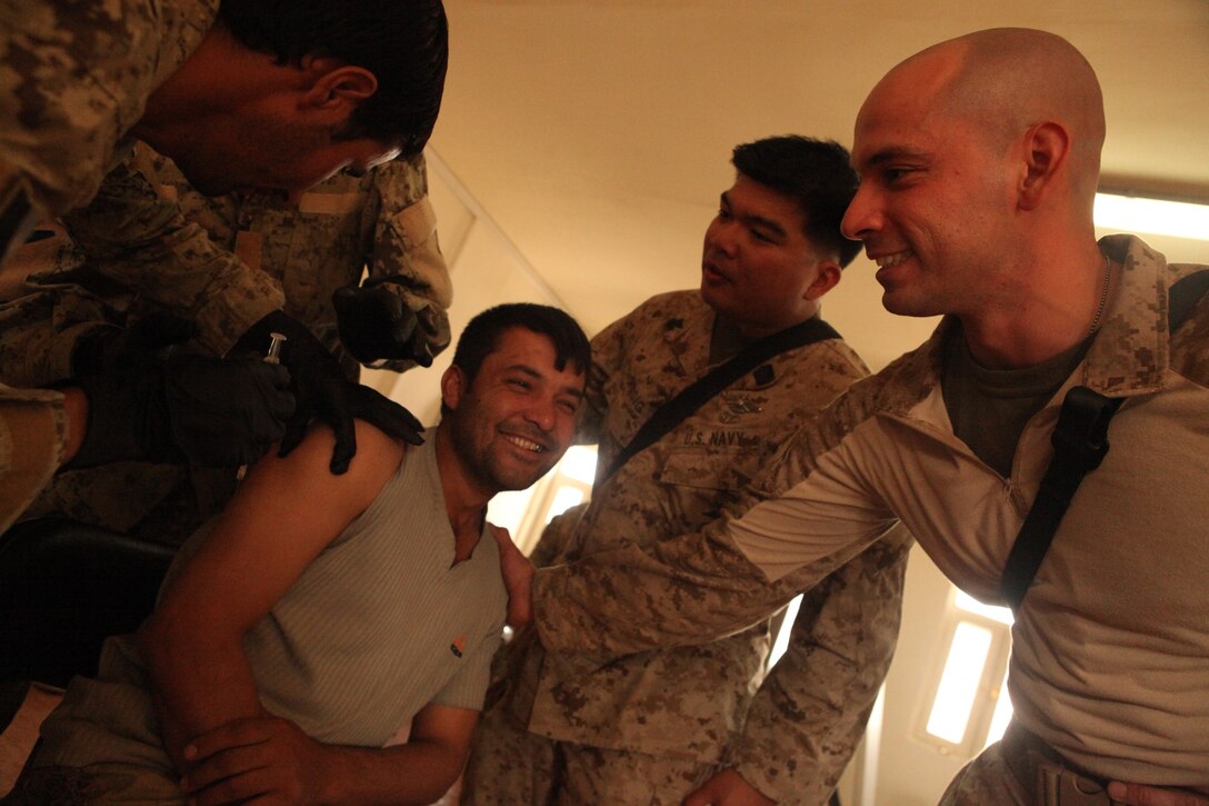 Petty Officer 1st Class Angelo Catindig, left, and Petty Officer 2nd Class Benjamin Reyes, both corpsmen with Marine Attack Squadron 513 comfort Naqeebullah, an Afghan police officer, after he receives a training shot during medical training at the joint regional Afghan center at Kandahar Airfield, Afghanistan, July 14.