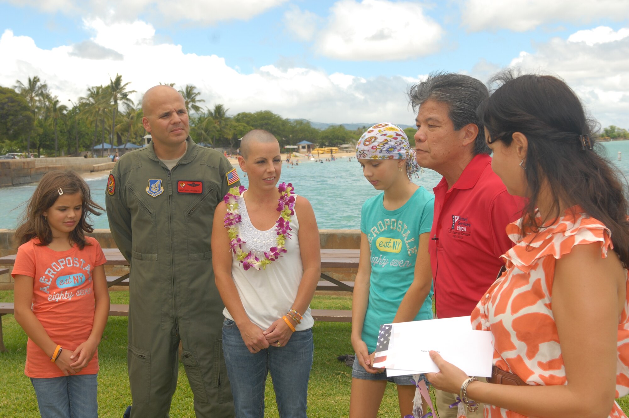 JOINT BASE PEARL HARBOR-HICKAM, Hawaii--Sophie Topouzoglou (third from left) stands with her family, (from left) Elena, younger sister; her father, Senior Master Sgt. Terry Topouzoglou, 535 Airlift Squadron; and mother, Jennifer. Sophie received the Oahu Armed Services YMCA Makeover Gift from Stanley Lum (second from left), Oahu Armed Services YMCA of Honolulu Executive Director, July 14, for surviving her battle with cancer. The YMCA makeover gift includes a makeover, dinner for her family, two-night stay at a hotel suite and a $250 gift certificate. (U.S. Air Force Photo/Ed Foster)