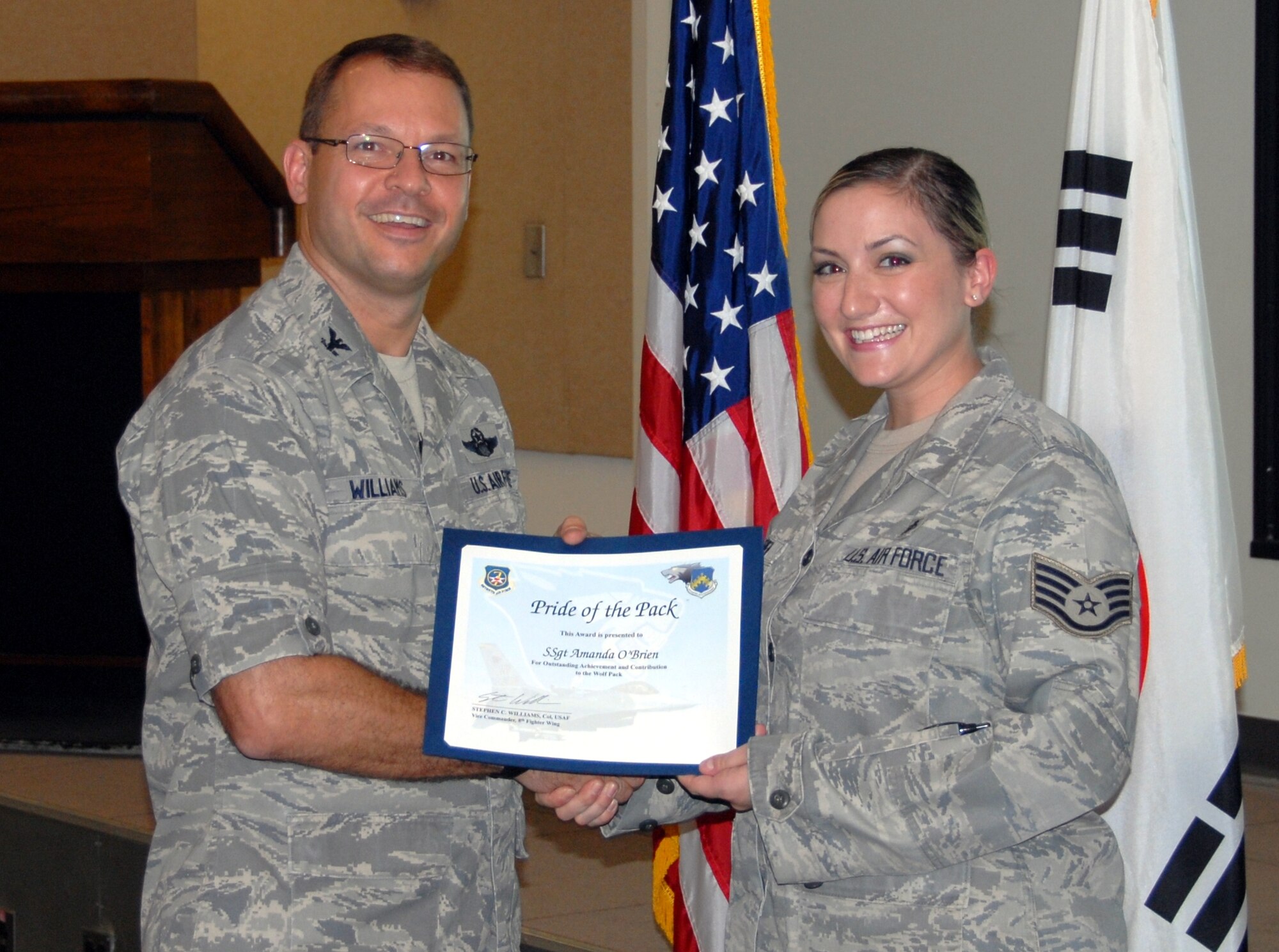 KUNSAN AIR BASE, Republic of Korea -- Col. Stephen Williams, 8th Fighter Wing vice commander, presents Staff Sgt. Amanda “Mae” O’Brien, 8th Medical Operations Squadron unit deployment manager, with a Pride of the Pack award here July 14. (U.S. Air Force photo/Capt. Omar Villarreal)