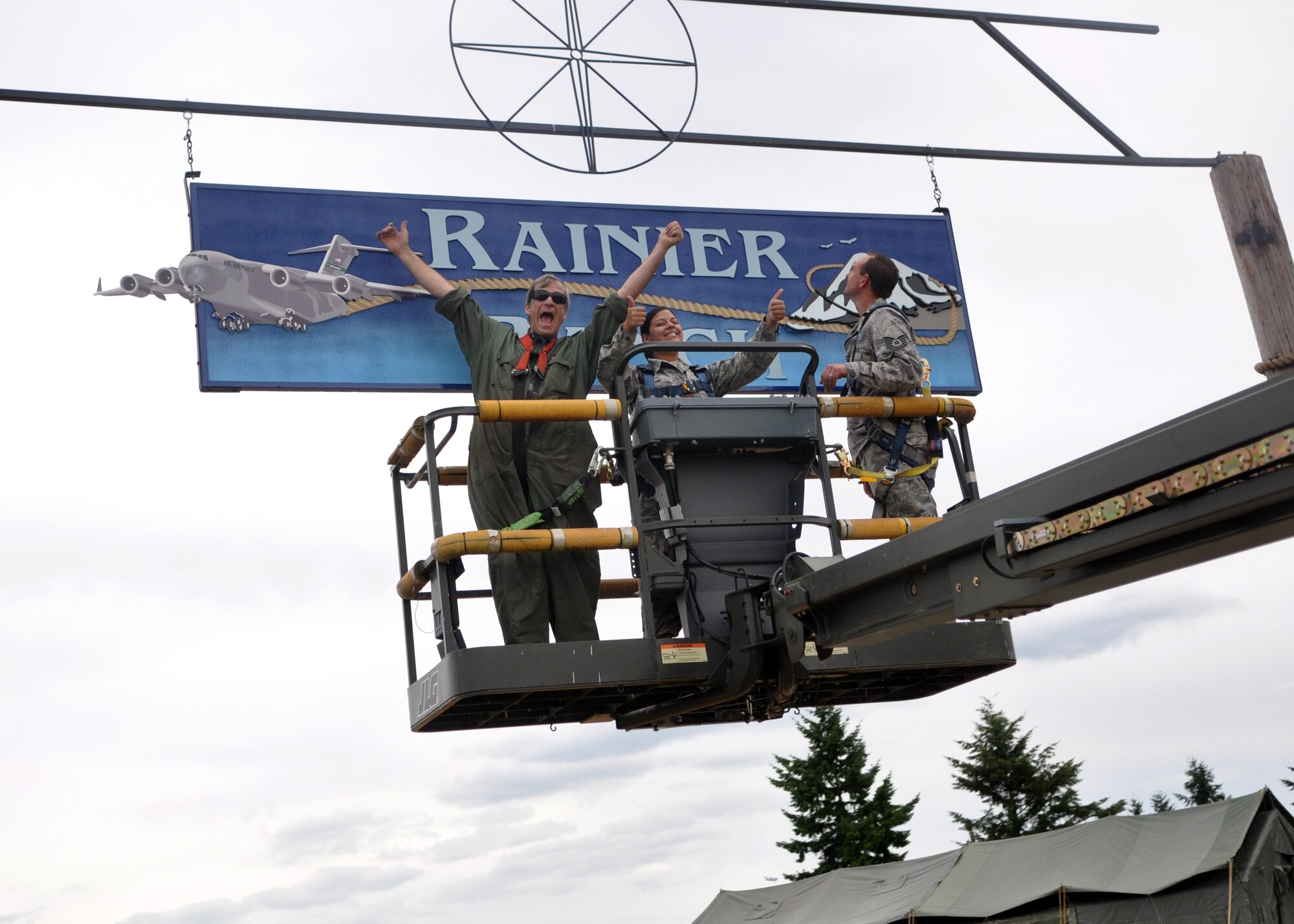 Mr. Craig Hays, left, Senior Airman Tiara Islam, center, and Tech. Sgt. Ivan Johnson, all 627th Civil Engineering Squadron structural support, celebrate the hanging of the Rainier Ranch sign July 11 at Joint Base Lewis-McChord, Wash. (U.S. Air Force photo/Airman 1st Class Leah Young)