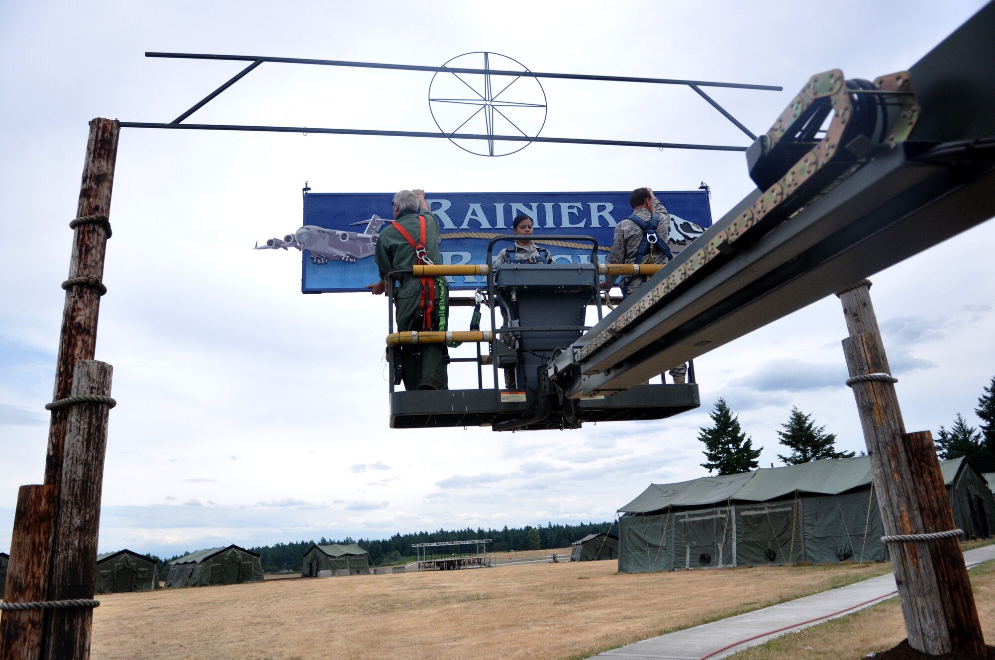 Mr. Craig Hays, left, Senior Airman Tiara Islam, center, and Tech. Sgt. Ivan Johnson, all 627th Civil Engineering Squadron structural support, prepare to hang the Rainier Ranch sign July 11 at Joint Base Lewis-McChord, Wash. (U.S. Air Force photo/Airman 1st Class Leah Young)