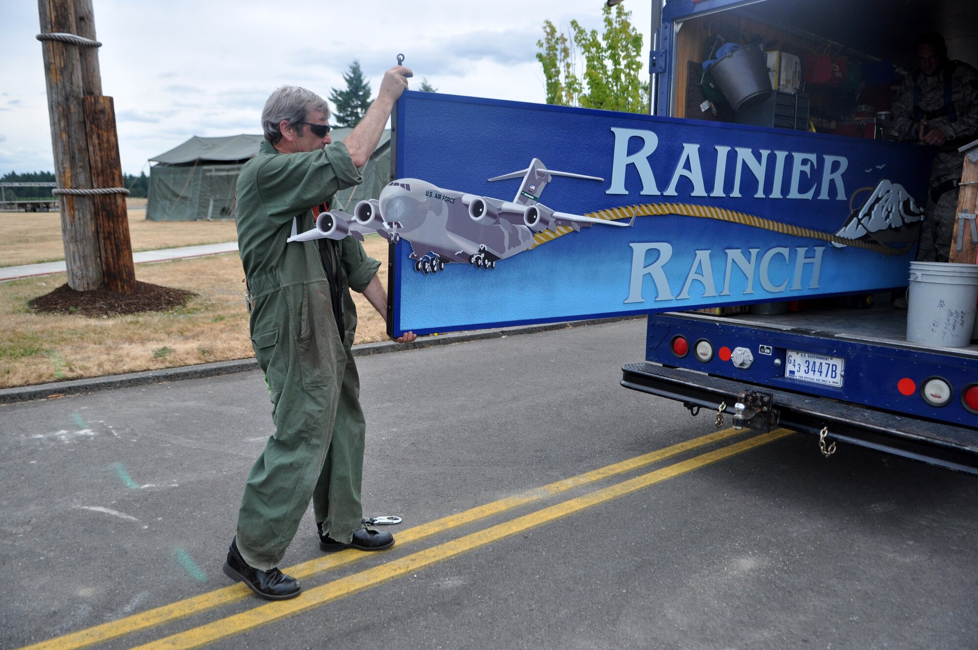Mr. Craig Hays, 627th Civil Engineering Squadron structural support, takes the Rainier Ranch sign out of the back of a truck July 11 at Joint Base Lewis-McChord, Wash. The installation will host Air Mobility Command Rodeo 2011, and competition is set to take place from July 23 to 29. McChord Field's Heritage Hill, with the addition of dozens of tents and a few hundred barrels of hay, is quickly being transformed into Rainier Ranch. (U.S. Air Force photo/Airman 1st Class Leah Young)