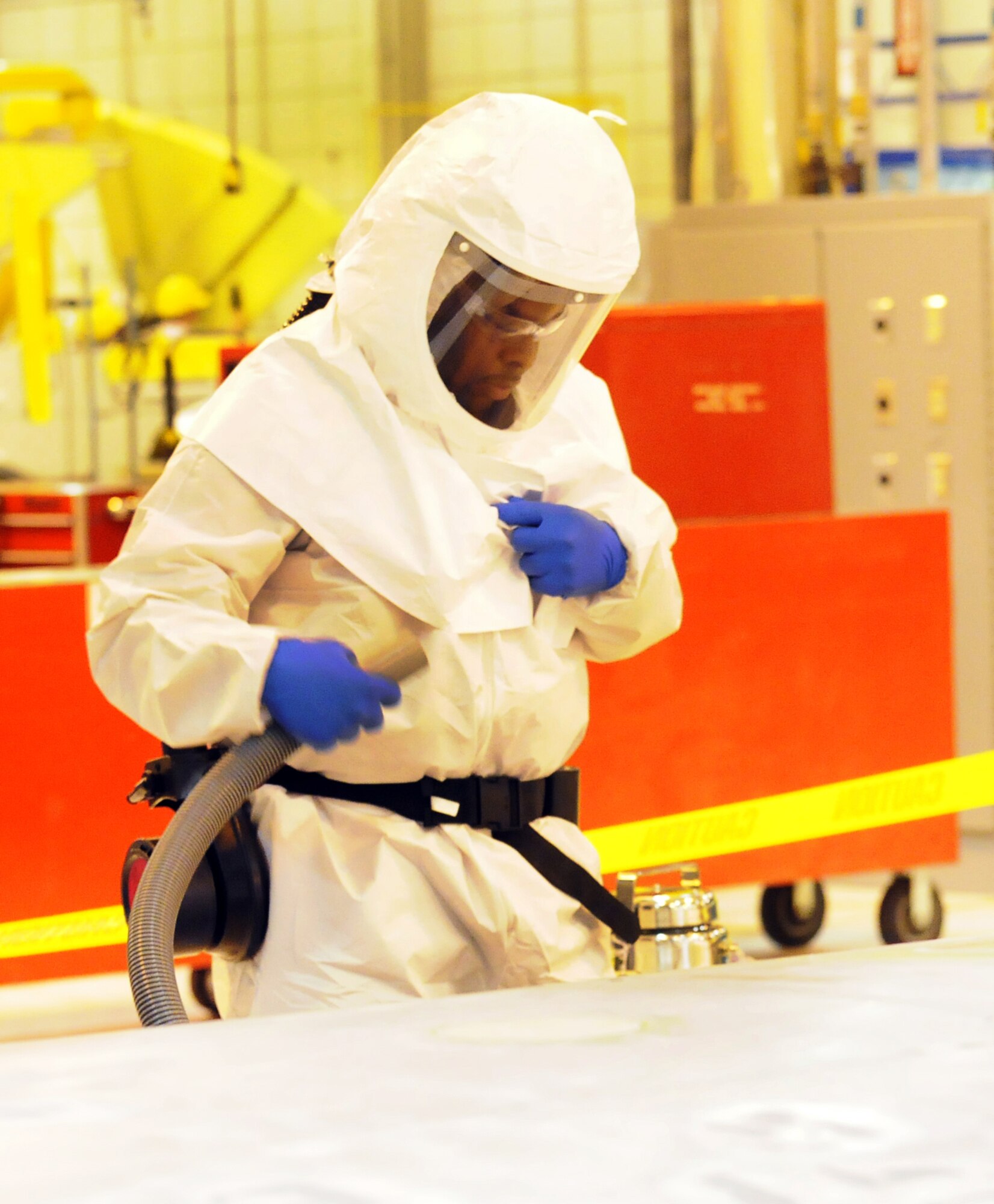Evan Roquemore suits up in protective gear and a respirator to demonstrate improved techniques with grinding or grit blasting under a containment bag. U. S. Air Force photo by Sue Sapp
