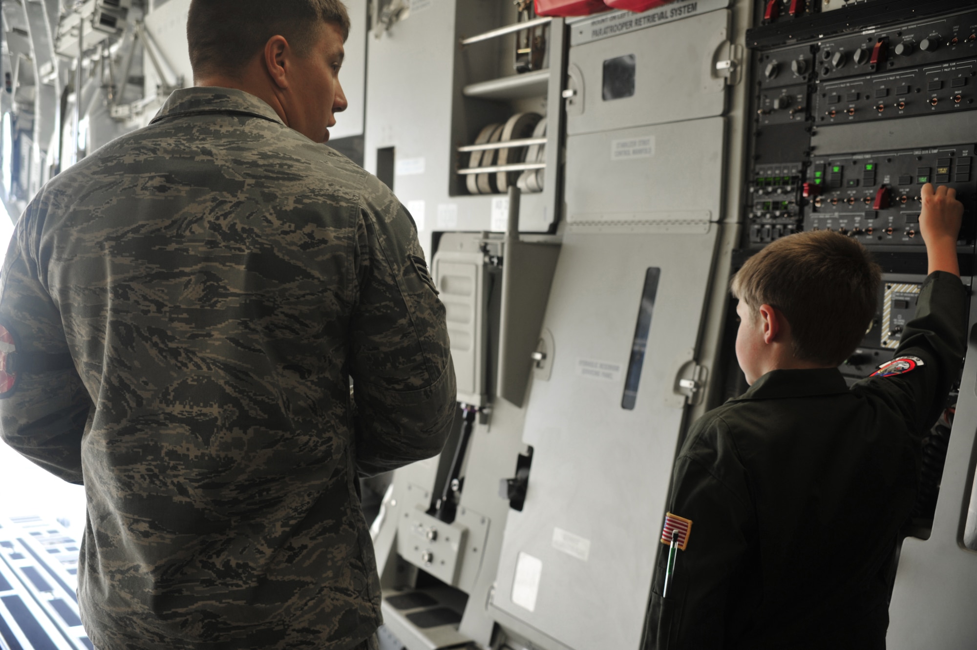Senior Airman Stephen Lanham, 62nd Aircraft Maintenance Squadron crew chief, instructs Evan Waara, "Pilot for a Day," on how to open the ramp doors of a C-17 Globemaster III July 7 at Joint Base Lewis-McChord, Wash. Evan also had an opportunity to sit in the cockpit of the C-17. (Air Force photo/Staff Sgt. Frances Kriss)