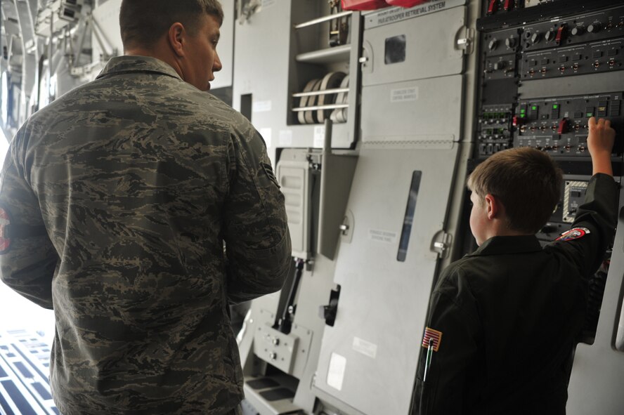 Senior Airman Stephen Lanham, 62nd Aircraft Maintenance Squadron crew chief, instructs Evan Waara, "Pilot for a Day," on how to open the ramp doors of a C-17 Globemaster III on July 7, 2011, at Joint Base Lewis-McChord, Wash. Evan also had an opportunity to sit in the cockpit of the C-17. (U.S. Air Force Photo/Staff Sgt. Frances Kriss)
