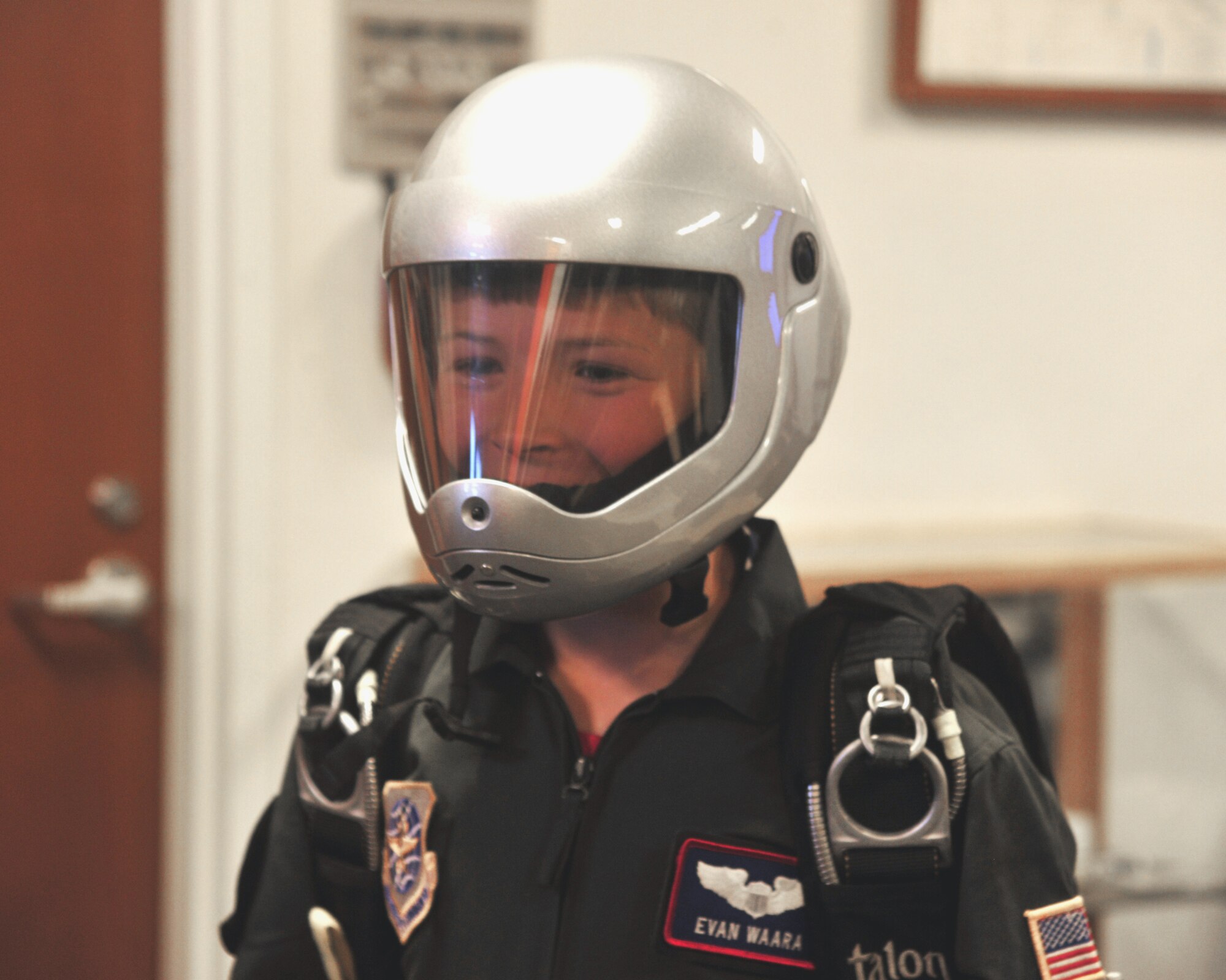 Evan Waara, "Pilot for a Day," tries on a real parachute and full-face helmet July 7 at Joint Base Lewis-McChord, Wash. Evan was part of the Pilot for a Day program, which devotes an entire day for local children with serious or chronic conditions and give them a chance to experience the Air Force firsthand. (Air Force photo/Staff Sgt. Frances Kriss)        