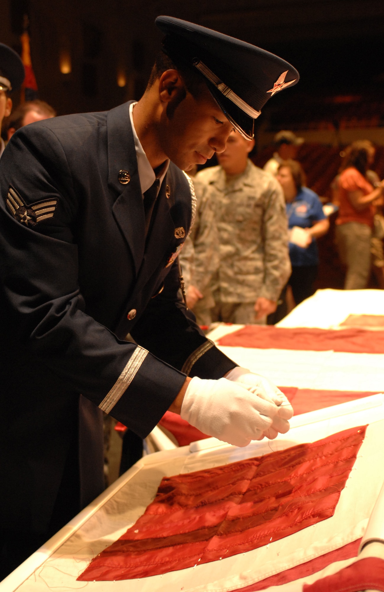 Davis-Monthan Air Force Base Honor Guard member Senior Airman Michael Jones places a stitch in the National 9/11 Flag at the Flag Stitching ceremony held at the University of Arizona’s Centennial Hall in Tucson, Ariz. July 8. The National 9/11 Flag Tour is a grassroots effort to repair the 30-foot flag that hung across from the Twin Towers and was damaged during the attacks of Sept. 11. Retired flags from across the 50 states are being used in the restoration. (U.S. Air Force photo by Airman 1st Class Saphfire Cook)
