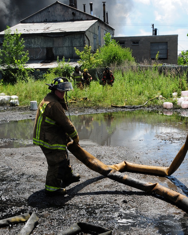 Niagara Falls Air Reserve Station Firefighters respond to a call for mutual aid support.  The three alarm fire at a warehouse in Buffalo started at approximately 5 a.m. on July 13, 2011.  Firefighter Jeff Gray, Ladder 14, Buffalo Fire Department and a First Sergeant with the 914th Maintenance Squadron moves a hose further away from the burning building that stored oil, grease, and propane. (U.S. Air Force Reserve photo by Peter Borys)