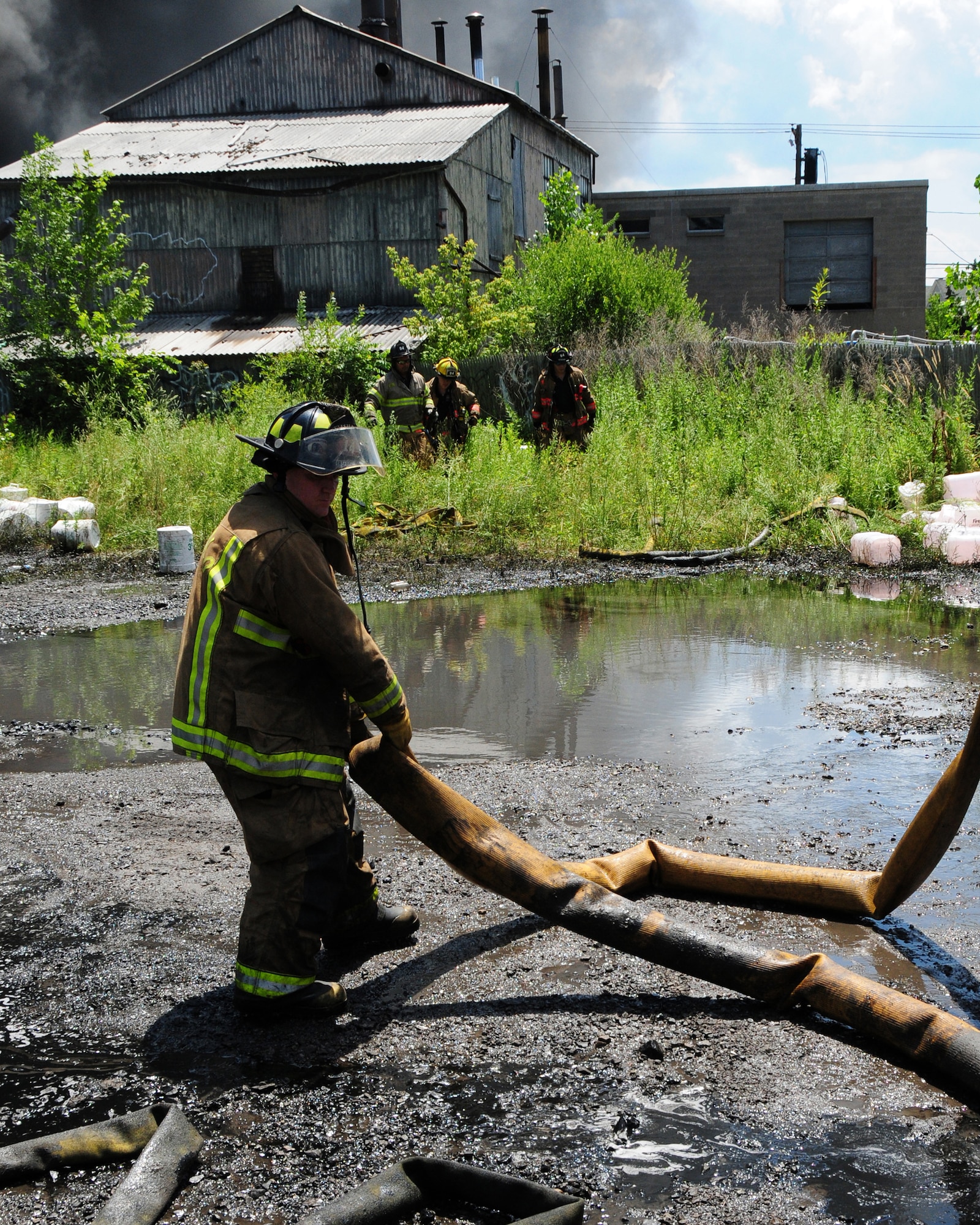 Niagara Falls Air Reserve Station Firefighters respond to a call for mutual aid support.  The three alarm fire at a warehouse in Buffalo started at approximately 5 a.m. on July 13, 2011.  Firefighter Jeff Gray, Ladder 14, Buffalo Fire Department and a First Sergeant with the 914th Maintenance Squadron moves a hose further away from the burning building that stored oil, grease, and propane. (U.S. Air Force Reserve photo by Peter Borys)