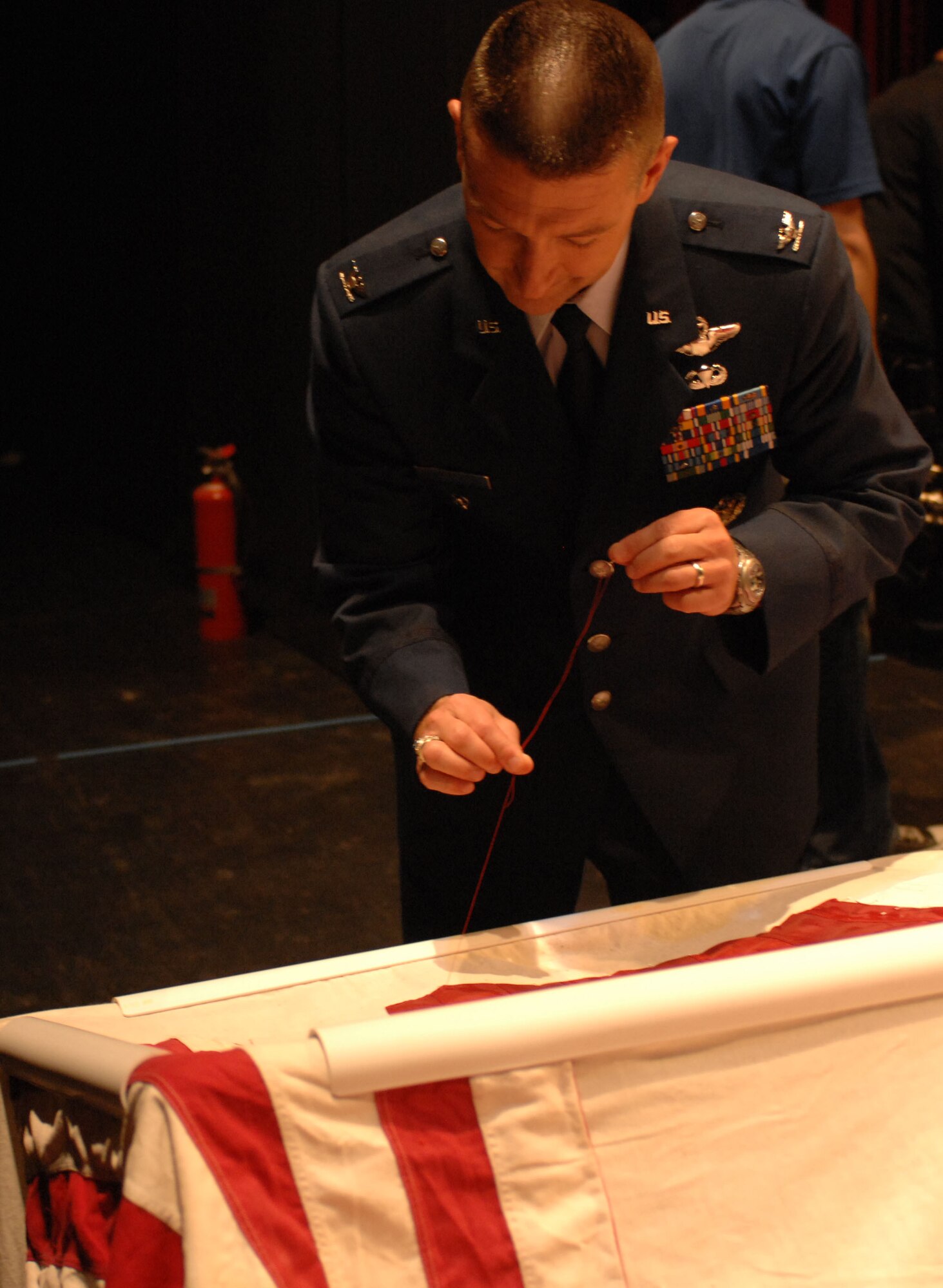 U.S. Air Force Col. Brian Hastings, 355th Fighter Wing vice commander, places a stitch in the National 9/11 Flag at the Flag Stitching ceremony held at the University of Arizona’s Centennial Hall in Tucson, Ariz. July 8. The National 9/11 Flag Tour is a grassroots effort to repair the 30-foot flag that hung across from the Twin Towers and was damaged during the attacks of Sept. 11. Retired flags from across the 50 states are being used in the restoration. (U.S. Air Force photo by Tech. Sgt. Russell Martin)
