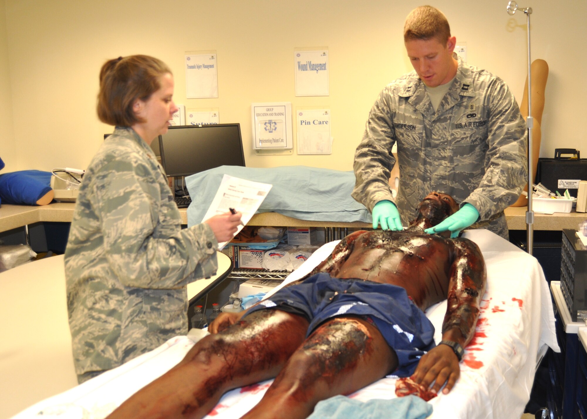 Maj. (Dr.) Heather Bright, 81st Surgical Operations Squadron, observes new surgery resident Capt. (Dr.) Jacob Anderson as he assesses “burn patient” Airman 1st Class Kenton Spencer during a June 15 advanced trauma life support training session. Dr. Anderson was among the new surgery and internal medicine residents who arrived at the hospital the first week of June. Dr. Bright explained the ATLS training was part of the orientation for the new residents to test their ability to manage patients involved in a trauma. Airman Spencer was among the four Aerospace Medical Apprentice Phase II course students who graduated June 17.  (U.S. Air Force photo by Steve Pivnick)