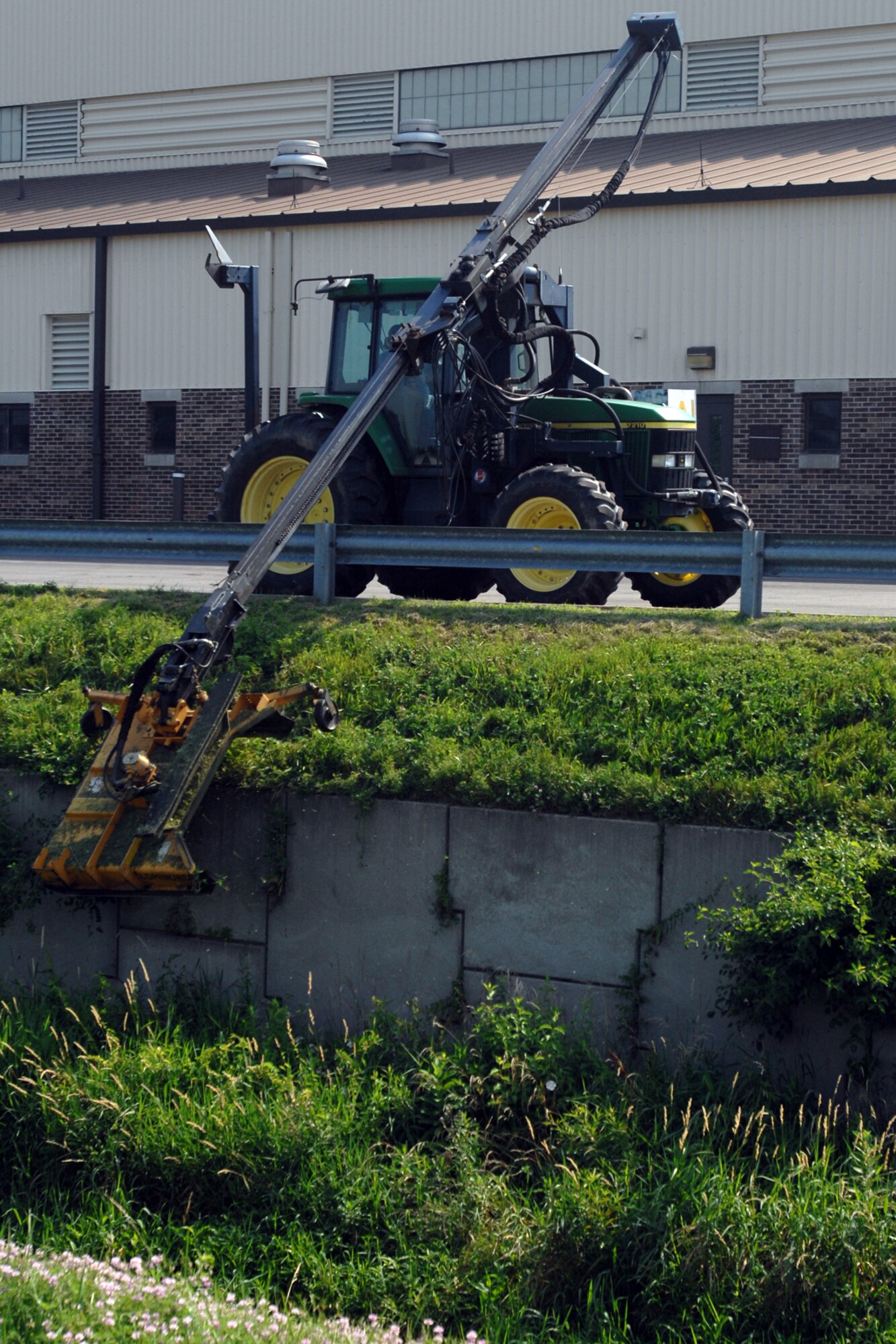 GRISSOM AIR RESERVE BASE, Ind. -- Curtis Elburn, an equipment operator with Data Monitor Systems, Inc., uses a slope mower to trim along the ditch between buildings 592 and 596. The long boom of the slope mower helps Mr. Elburn reach areas in difficult terrain. (U.S. Air Force photo/Tech. Sgt. Douglas Hays)