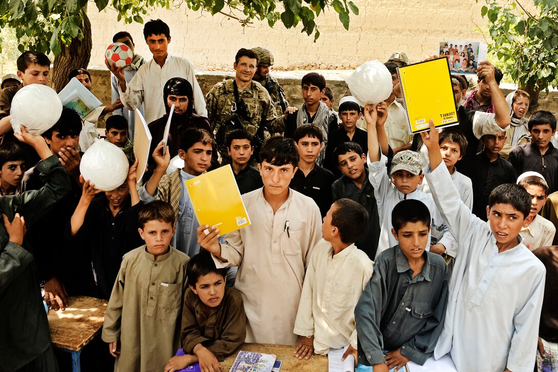 Afghan students at a boys school hold up their new school supplies and toys in the Alingar district of Laghman province, Afghanistan, July 13, 2011.