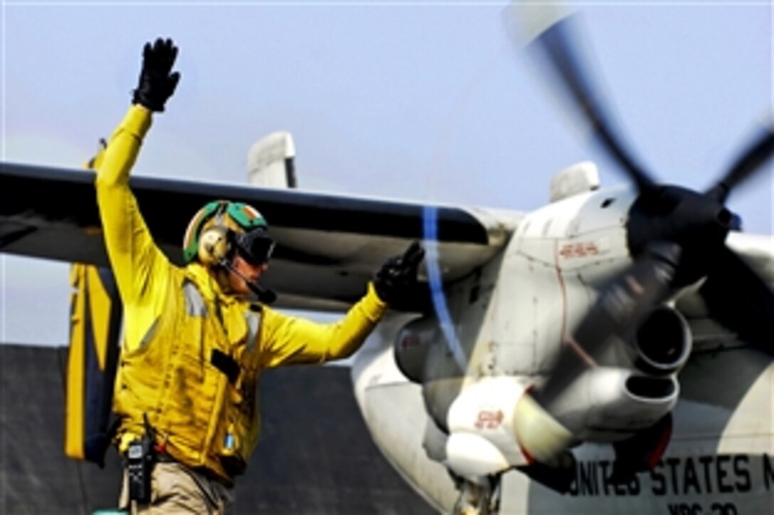 U.S. Navy Lt. Jerrod Washburn signals the launch of a C-2A Greyhound from the aircraft carrier USS Ronald Reagan in the Arabian Sea, June 30, 2011. Washburn is a flight deck shooter. The Greyhound is assigned to Fleet Logistics Combat Support Squadron 30. 