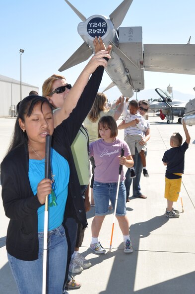 Visually-impaired students from Victoriano Elementary School in Moreno Valley, Calif., their teachers and parents, visit March Field June 30 for an aircraft tour. Here they feel the missiles attached to a 144th Fighter Wing F-16 Falcon. (U.S. Air Force photo by Linda Welz)

