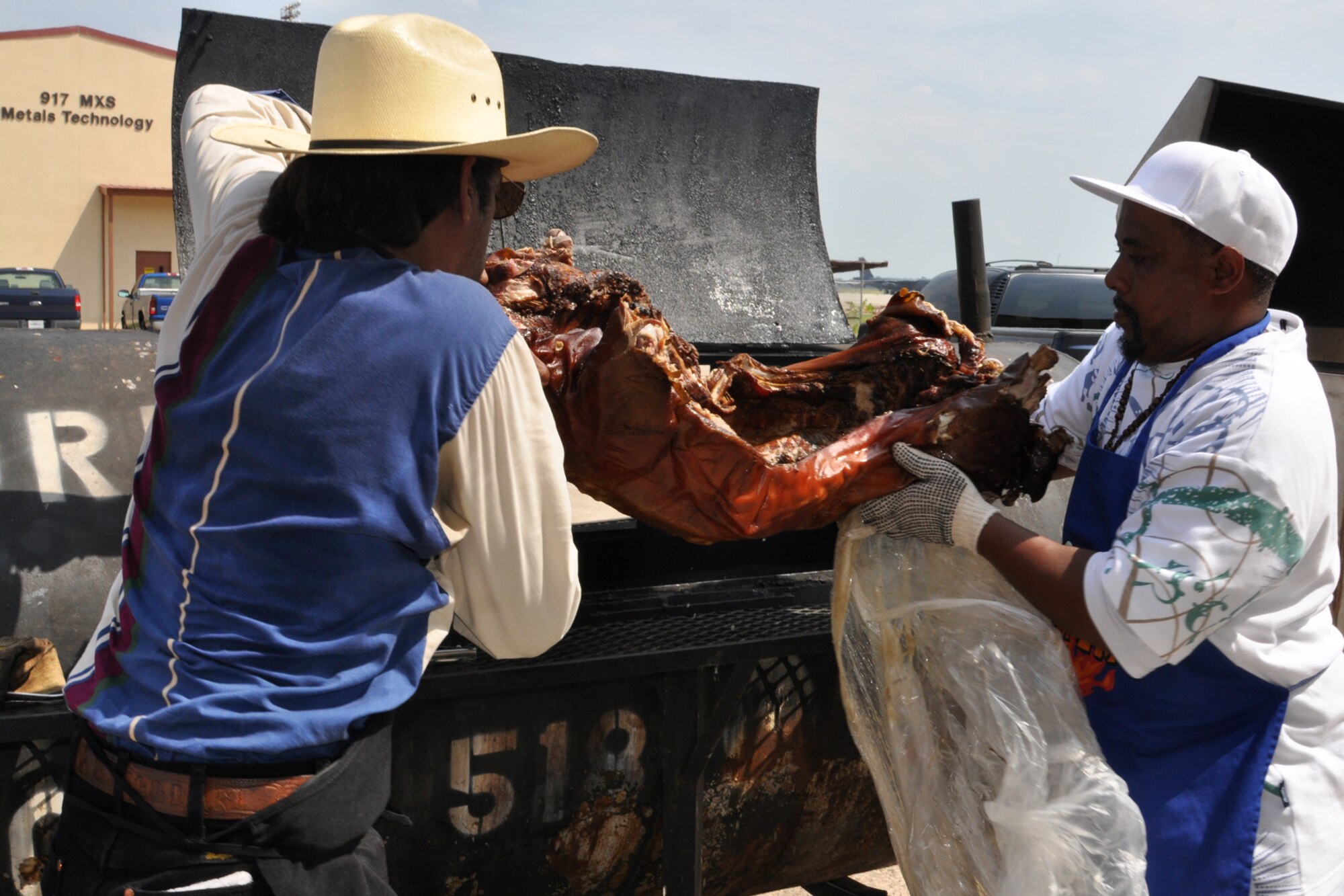 (L to R) W.W. Walker, owner of “Down Home Burger & BBQ Turkey on a Leg,” in Shreveport, La., and Roy Parson, load a pig into a grill to reheat it at Barksdale Air Force Base, La. July 15, 2011. Mr. Walker cooked the food at the celebration feast for Lt. Col. James Macaulay’s promotion to colonel. (U.S. Air Force photo/Tech. Sgt. Jeff Walston)  


