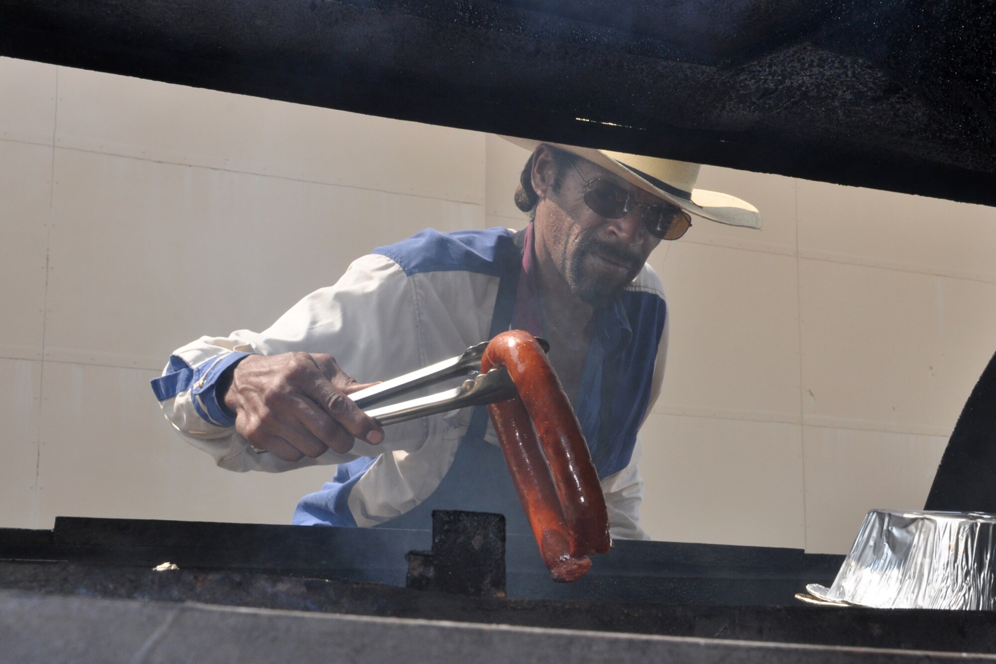 W.W. Walker, owner of “Down Home Burger & BBQ Turkey on a Leg,” in Shreveport, La., rearranges a grill to make room for a pig during a feast celebrating Lt. Col. James Macaulay’s promotion to colonel at Barksdale Air Force Base, La. July 15, 2011. (U.S. Air Force photo/Tech. Sgt. Jeff Walston)