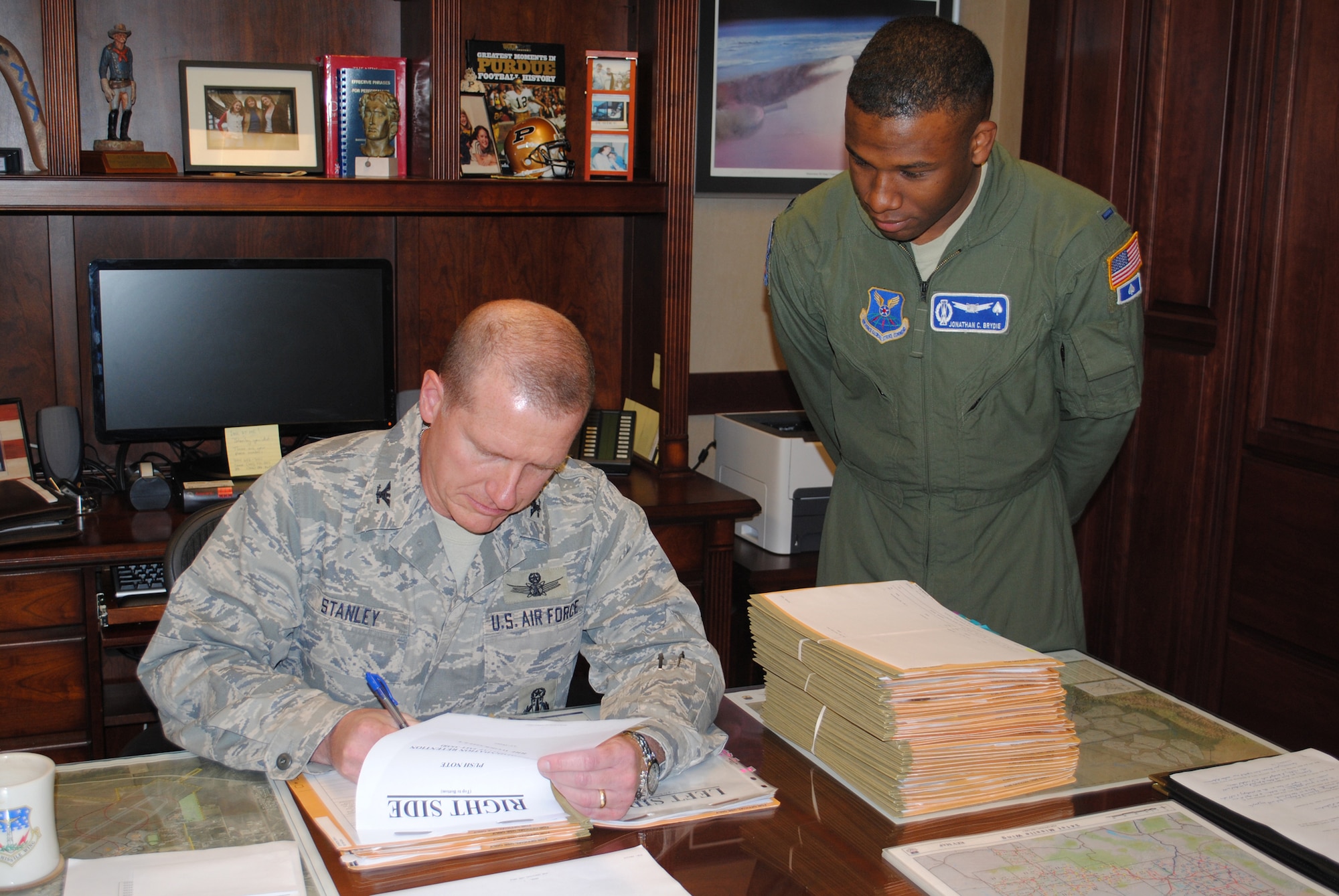 Col. Robert Stanley, 341st Missile Wing vice commander, finishes some paperwork as 1st Lt. Jonathan (Cory) Brydie, 10th Missile Wing Squadron missile combat crew commander, looks on. Stanley's ultimate goal is to support the commander in accomplishing his mission flawlessly. (U.S. Air Force photo/Airman Cortney Hansen)