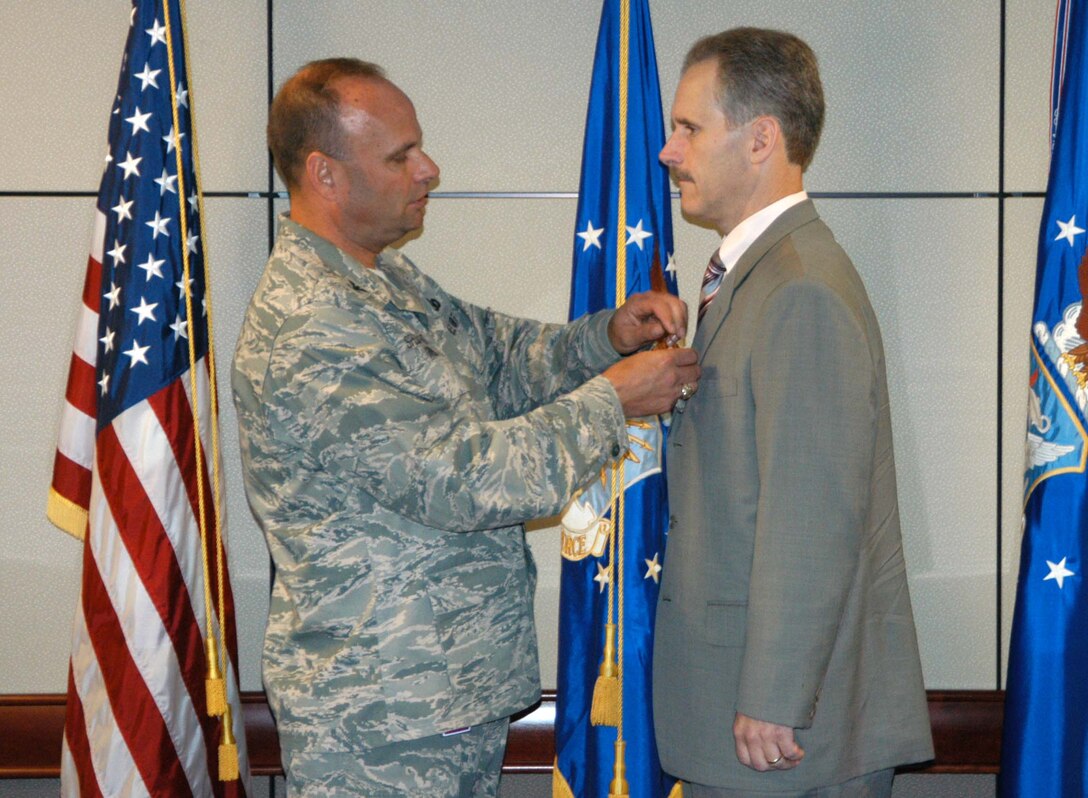 Col. Keith Givens, Air Force Office of Special Investigations vice commander, pins the Meritorious Civilian Service Award on Special Agent George Murphy. SA Murphy, a Naval Criminal Investigative Service member, received the award for his support of OSI's Warfighter Readiness and Execution Directorate. (U.S. Air Force Photo by Mr. James C. Dillard)