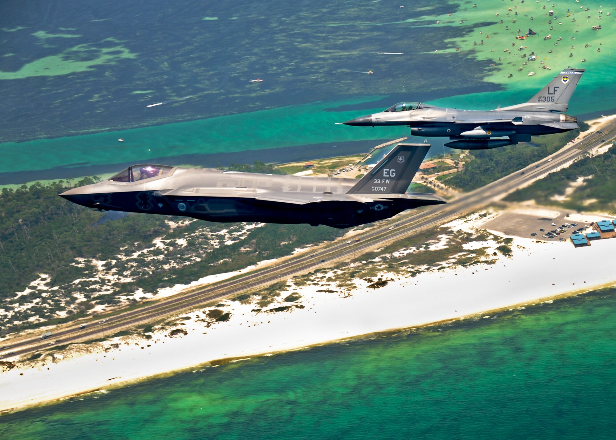 DOD’s first F-35 Lightning II joint strike fighter soars over Destin, Fla., with an F-16 Fighting Falcon before landing at its new home at Eglin Air Force Base, July 14.  Its pilot, Lt. Col. Eric Smith, of the 58th Fighter Squadron, is the first Air Force qualified JSF pilot.  (U.S. Air Force photo/Staff Sgt. Joely Santiago)