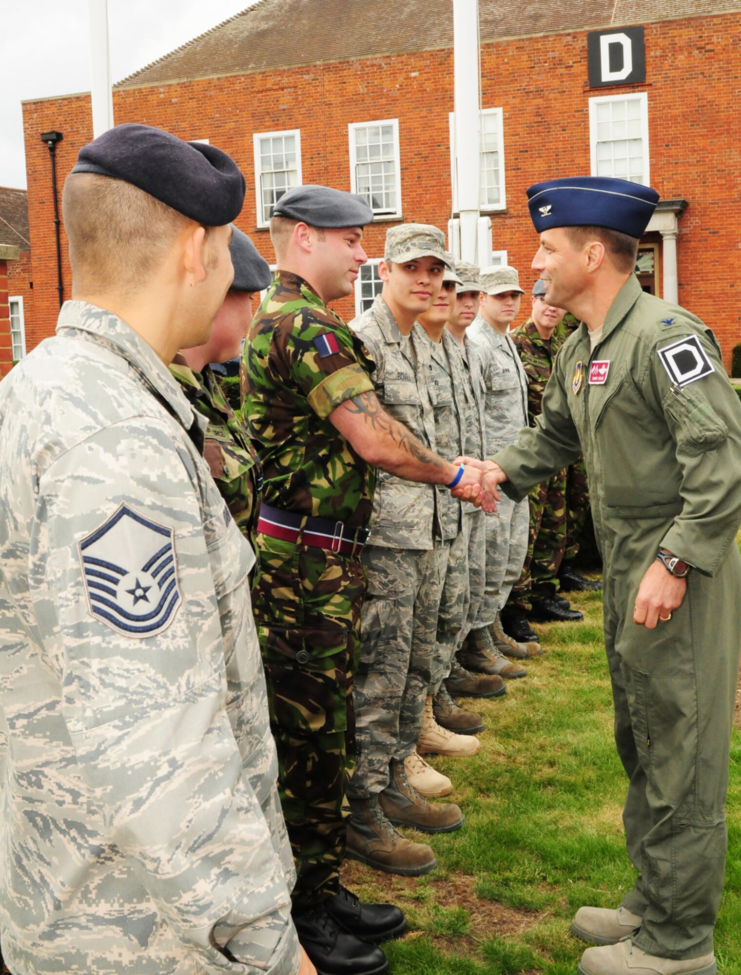 RAF MILDENHALL, England – Cpl. Brett Taylor, Royal Air Force Marham lacrosse team member, receives a coin as he shakes hands with Col. Christopher Kulas, 100th Air Refueling Wing commander, July 8, 2011. The coin was given as a special award from the British-American Committee, and was presented to all members of the lacrosse team. The team is made up of both RAF and U.S. Airmen. Members of the 100th Civil Engineer Squadron also received the award, along with Geoff Pleasance, an English artist who has painted murals both in the Galaxy Club and 95th Reconnaissance Squadron. (U.S. Air Force photo/Karen Abeyasekere)