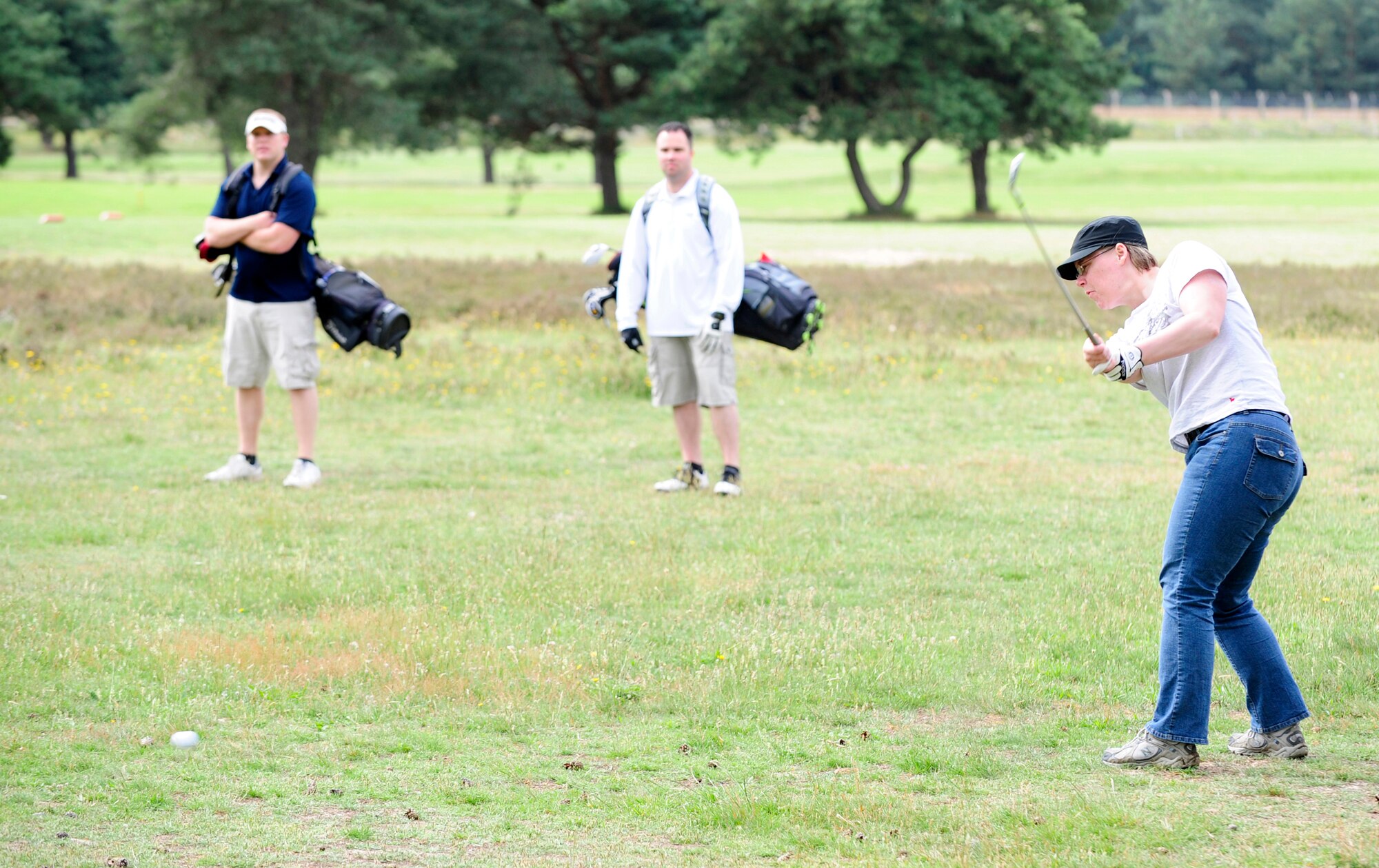 RAF MILDENHALL, England -- Cassandra Denton, 100th Communications Squadron, plays a punch shot under the trees on the 11th hole during the RAF Mildenhall Intramural Golf play-offs at Breckland Pines Golf Club, RAF Lakenheath, July 12, 2011. Brian Szarek (blue shirt) and Jonathan Barnes (white shirt), playing in opposition for the 100th Maintenance Squadron, were one hole up on the back nine. (U.S. Air Force photo/Senior Airman Ethan Morgan)