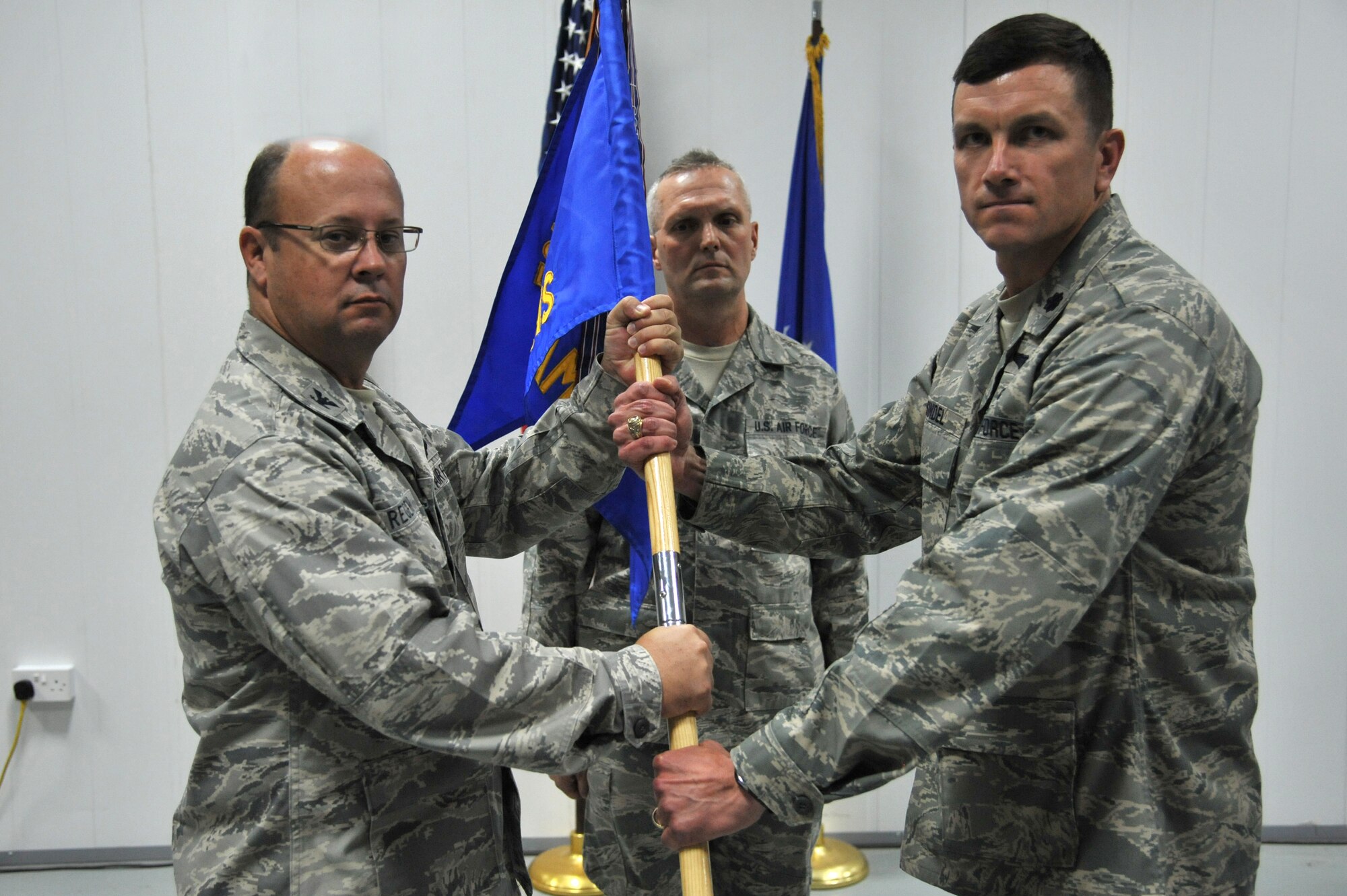Col. James Regenor, 521st Air Mobility Operations Group commander, left, passes the 5th Expeditionary Air Mobility Squadron guide-on to Lt. Col. Colin Sindel during a change of command ceremony July 14 at an undisclosed location in Southwest Asia. Colonel Sindel assumed command of the 5th EAMS from Lt. Col. Aaron Gtitner.  (U.S. Air Force photo by Master Sgt. Carlotta Holley)