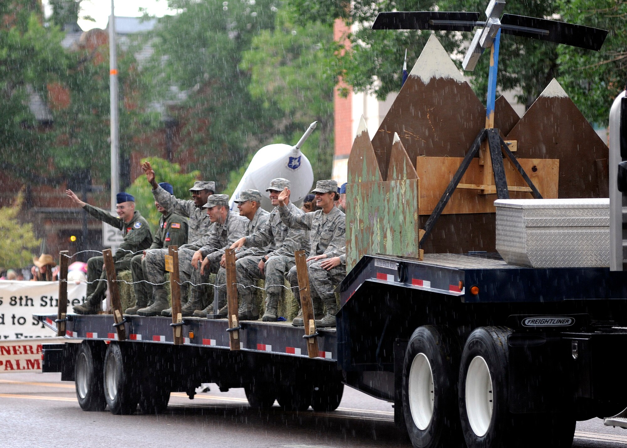 SCHRIEVER AIR FORCE BASE, Colo. -- Team Schriever members didn't let a little rain dampen their spirit while they wave at the crowd in downtown Colorado Springs that came out to the 71st annual Pikes Peak or Bust Rodeo Days Kick-Off Parade, July 12.  All parade proceeds go directly toward a scholarship fund for children and spouses of local fallen or wounded soldiers. (U. S. Air Force photo/David Ahlschwede) 
