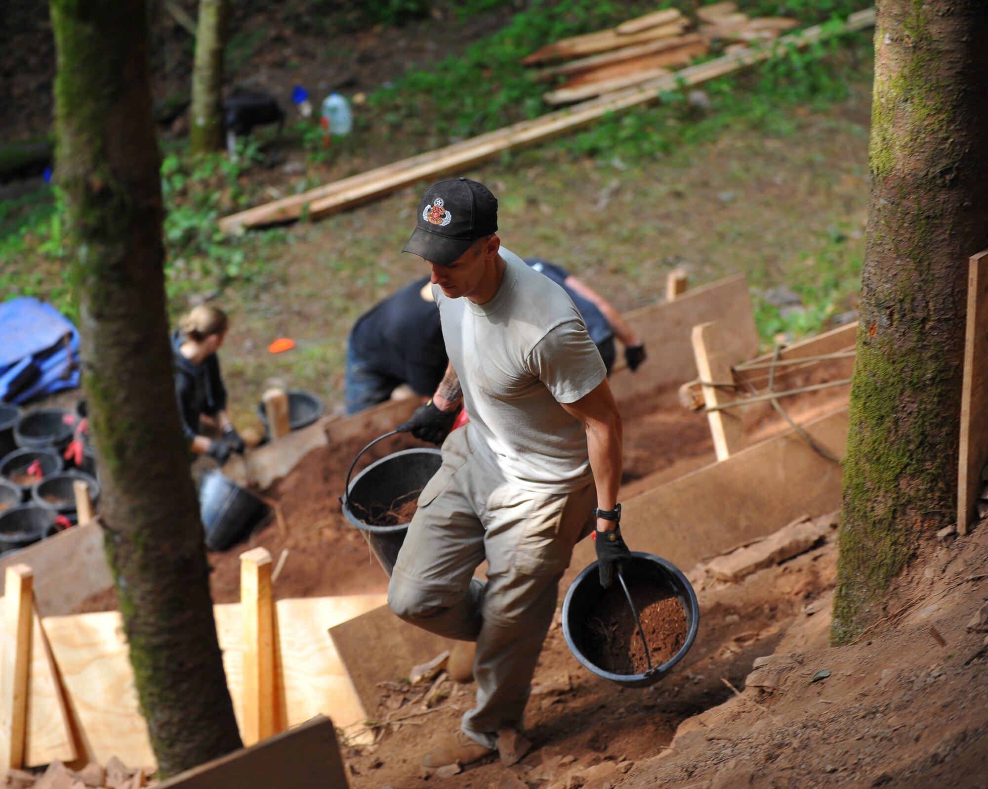 BETTENFELD, Germany – U.S. Army Sgt. Eric Dean, assigned to the Joint Prisoner of War, Missing in Action Accounting Command, out of Honolulu, carries buckets of dirt and rock to a sifting station at an excavation site here July 12. The mission of the JPAC team here is to organize the search and recovery of unaccounted-for American service members from World War II. (U.S. Air Force photo/Airman 1st Class Dillon Davis)