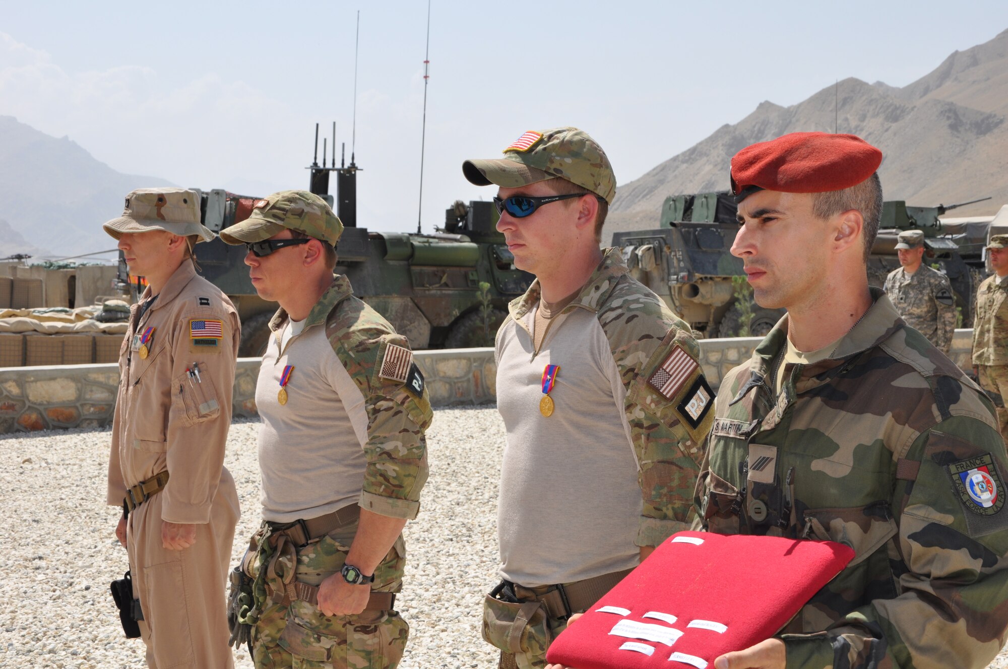 BAGRAM AIRFIELD, Afghanistan -- Capt. John Mosier, 83rd Expeditionary Rescue Squadron HH-60G Pave Hawk pilot, Tech. Sgt. Kristopher Burridge and Senior Airman Jackson Rogers, both 83 ERQS pararescue jumpers, stand at attention of being presented with the French National Defense Gold Medal with bronze star during a ceremony at Forward Operating Base Morales-Frazier July 8. (U.S. Air Force photo/Staff Sgt. John Wright)