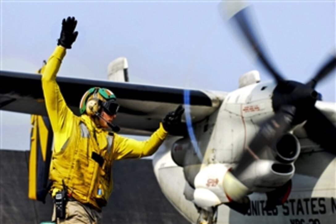 U.S. Navy Lt. Jerrod Washburn signals the launch of a C-2A Greyhound from the aircraft carrier USS Ronald Reagan (CVN 76) in the Arabian Sea on June 30, 2011.  Washburn is a flight deck shooter.  The Greyhound is assigned to Fleet Logistics Combat Support Squadron 30.  