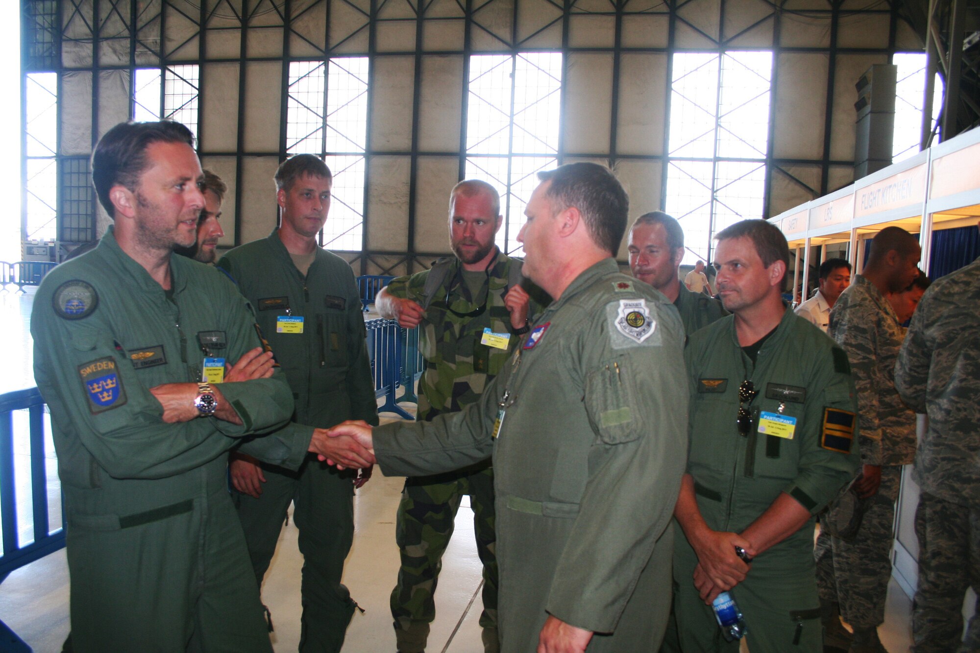 Maj. Patrick Linson, from Air Mobility Command's Detachment 5 at St. Joseph, Mo., welcomes participants from the Sweden air force arriving for the 2011 International Airdrop Symposium inside a hangar at Joint Base Lewis-McChord, Wash., on July 18, 2011. Linson is the chairperson for the symposium. (U.S. Air Force Photo/Master Sgt. Scott T. Sturkol)