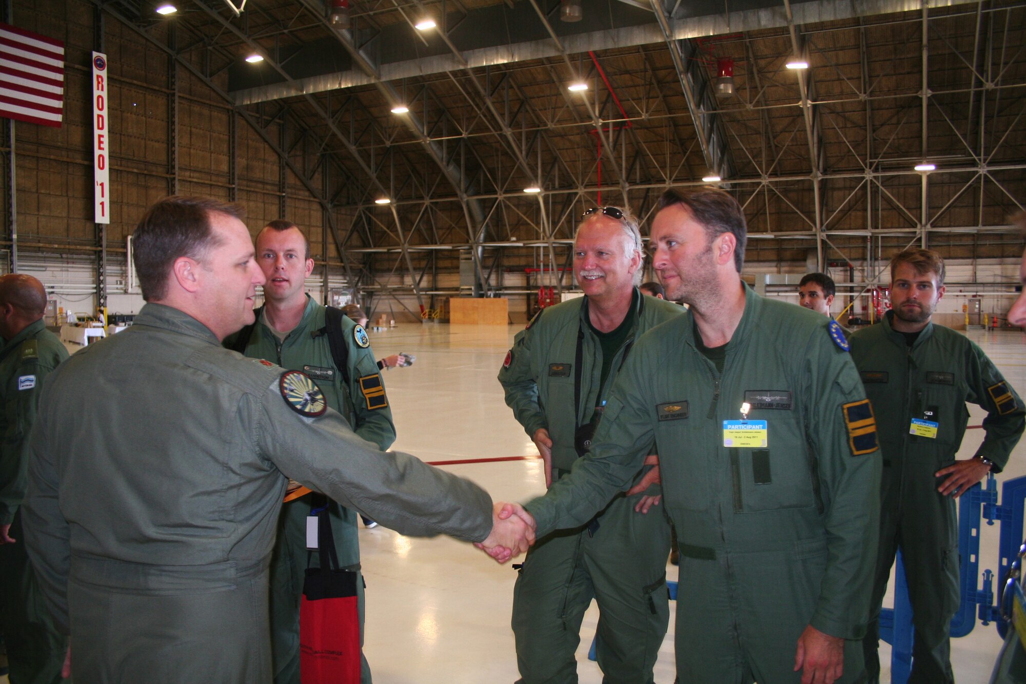 Maj. Patrick Linson, from Air Mobility Command's Detachment 5 at St. Joseph, Mo., welcomes participants from the Sweden air force arriving for the 2011 International Airdrop Symposium inside a hangar at Joint Base Lewis-McChord, Wash., on July 18, 2011. Linson is the chairperson for the symposium. (U.S. Air Force Photo/Master Sgt. Scott T. Sturkol)