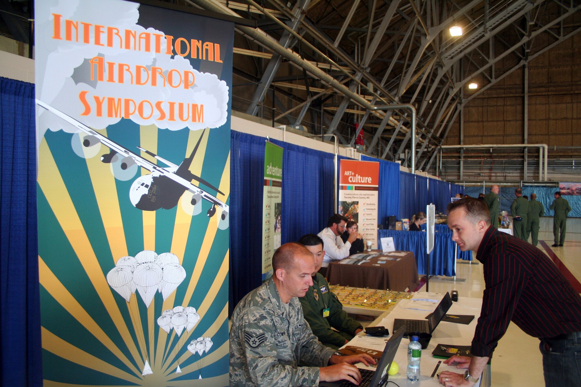 Staff Sgt. Owen Compton and Maj. Shane Noyes, both from Air Mobility Command's Detachment 5 at St. Joseph, Mo., work with participants arriving for the 2011 International Airdrop Symposium inside a hangar at Joint Base Lewis-McChord, Wash., on July 17, 2011. (U.S. Air Force Photo/Master Sgt. Scott T. Sturkol)
