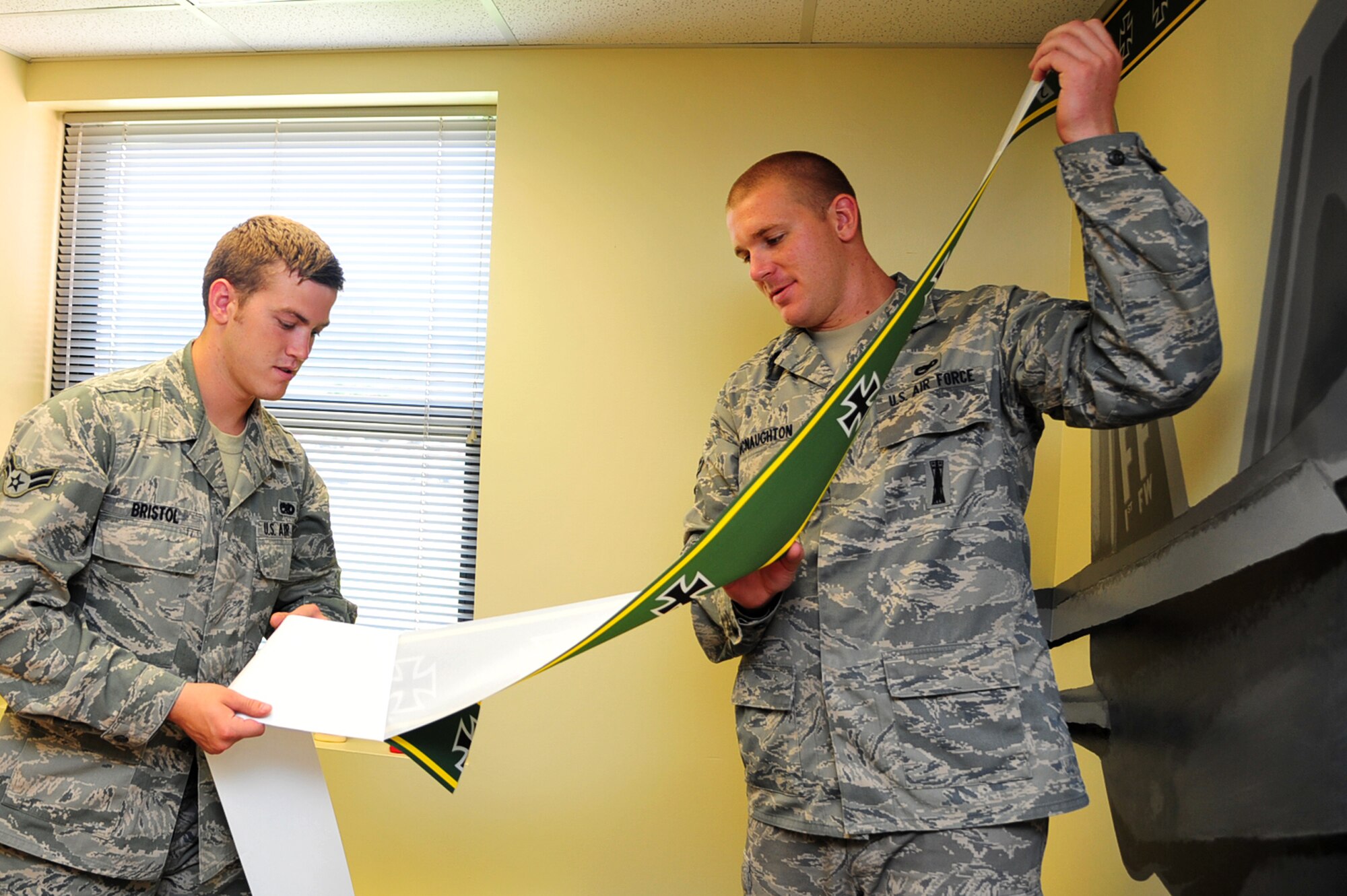 Airman 1st Class Jacob Bristol and Shane McNaughton, 1st Maintenance Squadron precision guided missile technicians, add a wallpaper border to the Airmen Leadership School Eagle flight classroom at Langley Air Force Base, Va., July 15, 2011. Airmen from the 1st Fighter Wing Airmen designed and renovated the Eagle Flight heritage room to preserve 1st FW heritage. (U.S. Air Force photo by Airman 1st Class Camilla Griffin/Released) 