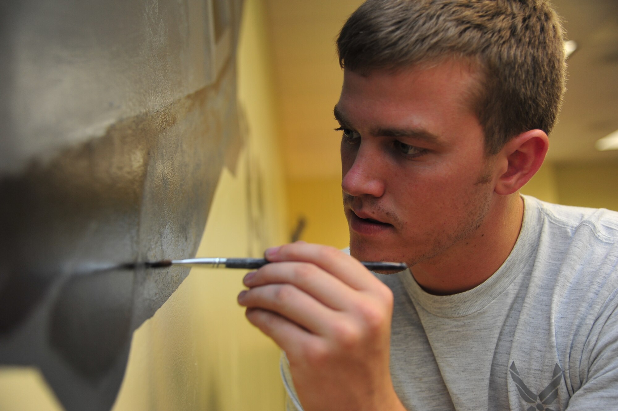 Airman 1st Class Jacob Bristol, 1st Maintenance Squadron precision guided missile technician, adds some finishing touches to an F-22 mural at Langley Air Force Base, Va., July 13, 2011. Members of the 1st Fighter Wing painted the mural to display the heritage of 1st FW. (U.S. Air Force photo by Airman 1st Class Camilla Griffin/Released)