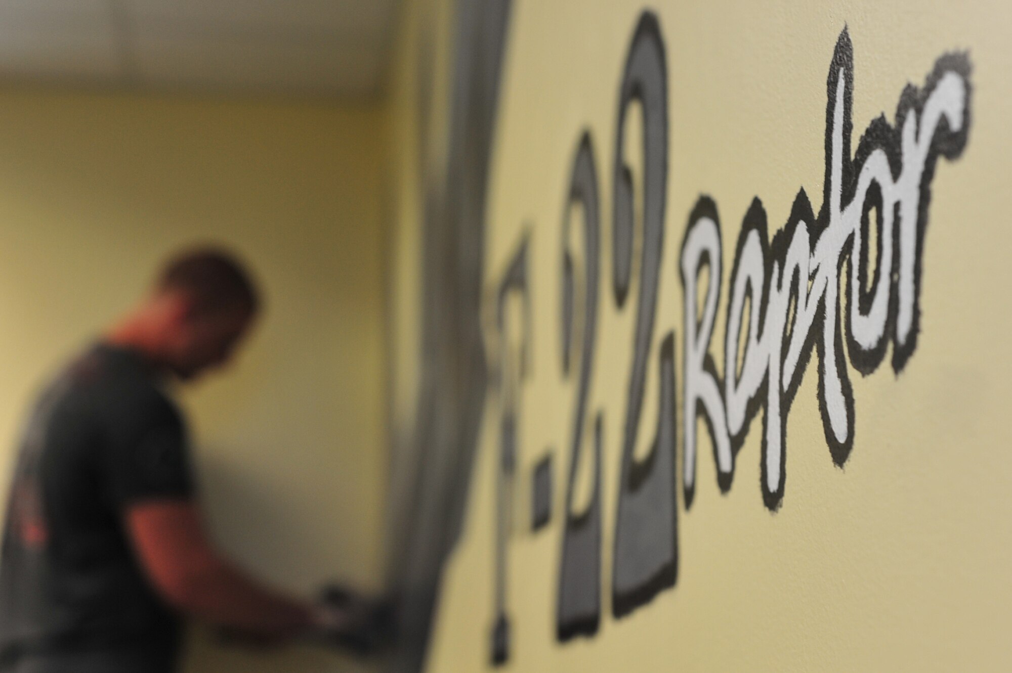 Airman 1st Class Shane McNaughton, 1st Maintenance Squadron precision guided missile technician, adds detail to an F-22 Raptor mural at Langley Air Force Base, Va., July 13, 2011. The mural is a gift to the Airman Leadership School from the 1st Fighter Wing to honor 1st FW heritage. (U.S. Air Force photo by Airman 1st Class Camilla Griffin/Released)