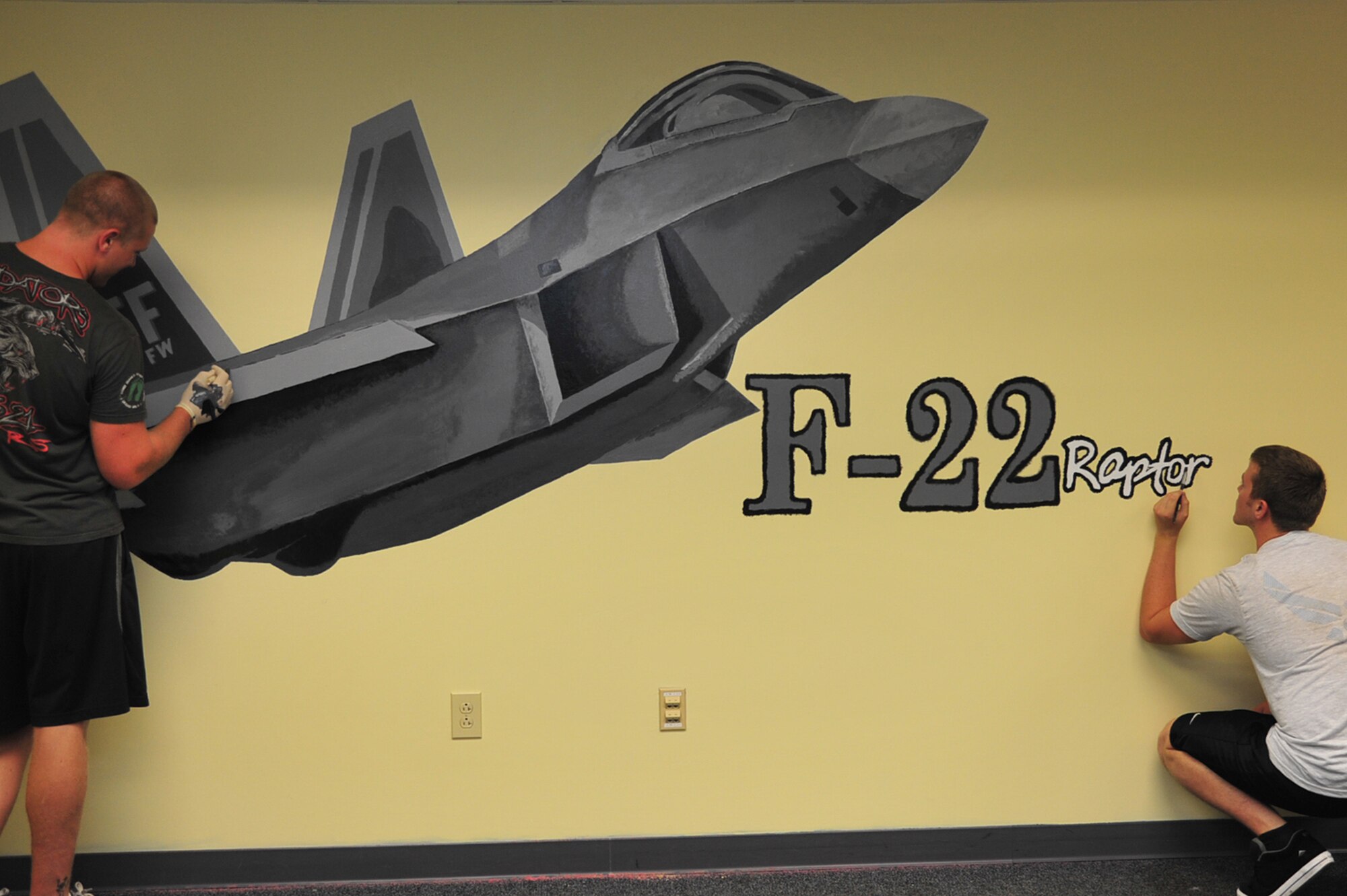 Airmen 1st Class Jacob Bristol and Shane McNaughton, 1st Maintenance Squadron precision guided missile technicians, add color to an F-22 Raptor mural at Langley Air Force Base, Va., July 13, 2011. The mural is a way for the 1st Fighter Wing to stay prominent to the Airmen that attend Airmen Leadership School. (U.S. Air Force photo by Airman 1st Class Camilla Griffin/Released)