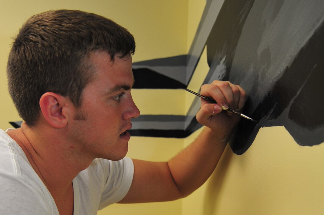 Airman 1st Class Jacob Bristol, 1st Maintenance Squadron precision guided missile technician, adds some finishing touches on an F-22 Raptor mural at Langley Air Force Base, Va., July 12, 2011. Volunteers spent nearly a week perfecting the painting in the Airman Leadership School eagle flight classroom. (U.S. Air Force photo by Airman 1st Class Camilla Griffin/Released)