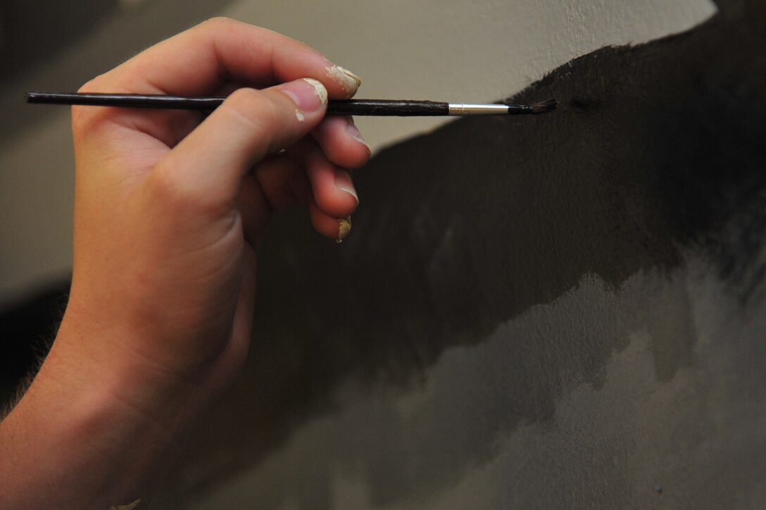 Airman 1st Class Jacob Bristol, 1st Maintenance Squadron precision guided missile technician, touches up the paint on a F-22 mural at Langley Air Force Base, Va., July 12, 2011. The mural is a gift to Airman Leadership School from the 1st Fighter Wing to honor 1st FW heritage. (U.S. Air Force photo by Airman 1st Class Camilla Griffin/Released)