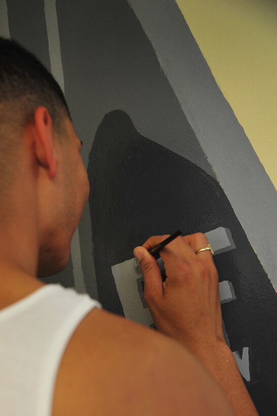 Airman 1st Class Israel Medina, 1st Operations Support Squadron air crew flight equipment technician, paints an F-22 Raptor’s tail number on a mural at Langley Air Force Base, Va., July 12, 2011. The F-22 mural is located in the Eagle flight classroom of the Airmen Leadership School. (U.S. Air Force photo by Airman 1st Class Camilla Griffin/Released)
