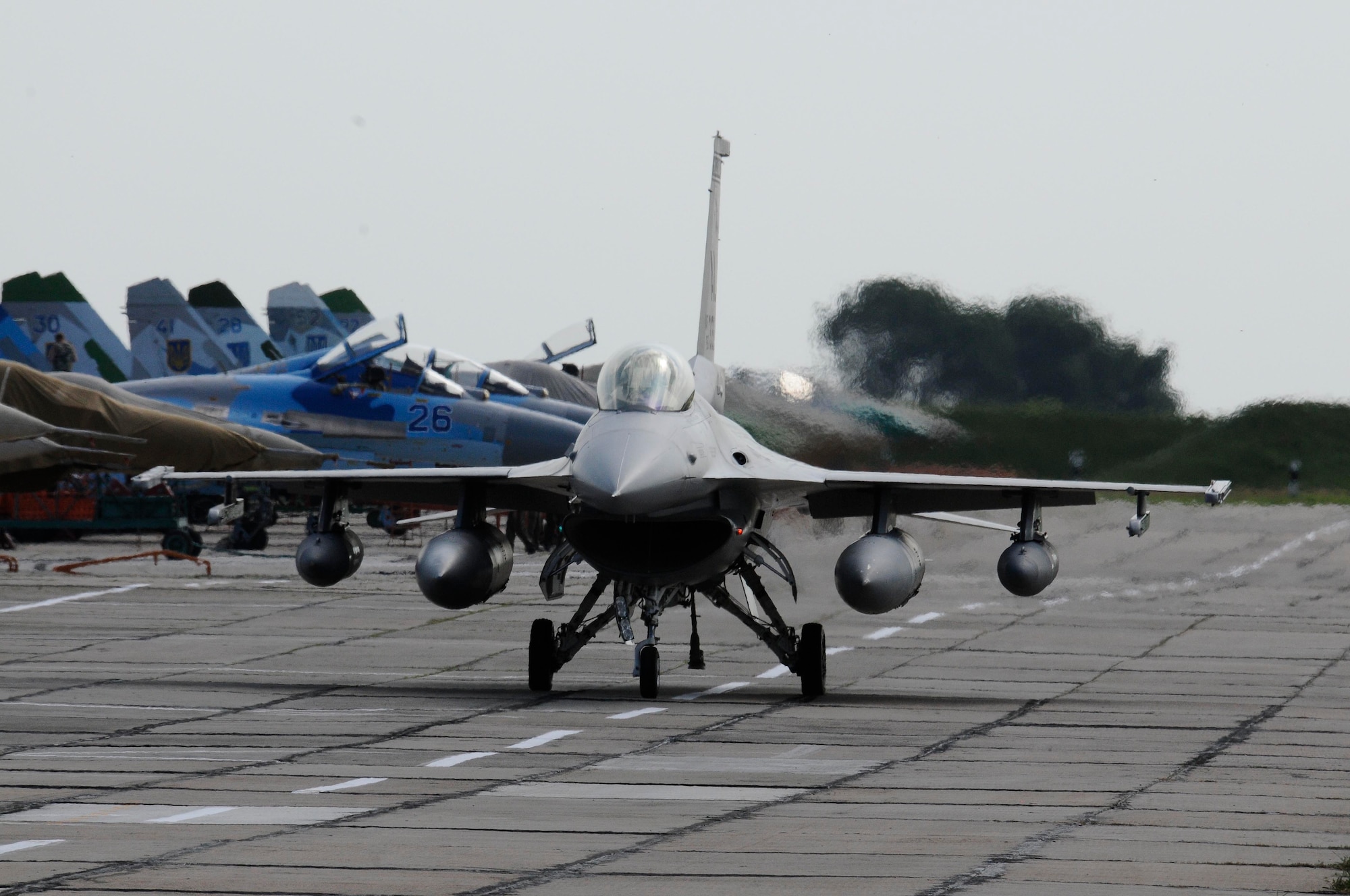 An F-16 Fighting Falcon from the Alabama Air National Guard taxis on the ramp at Mirgorod Air Base, Ukraine, July 16, 2011, passing Ukrainian SU-27s and MIG-29s. The U.S. fighters arrived for SAFE SKIES 2011, a joint Ukraine, Poland and U.S. aerial exchange event. (U.S. Air Force photo/Tech. Sgt. Charles Vaughn)