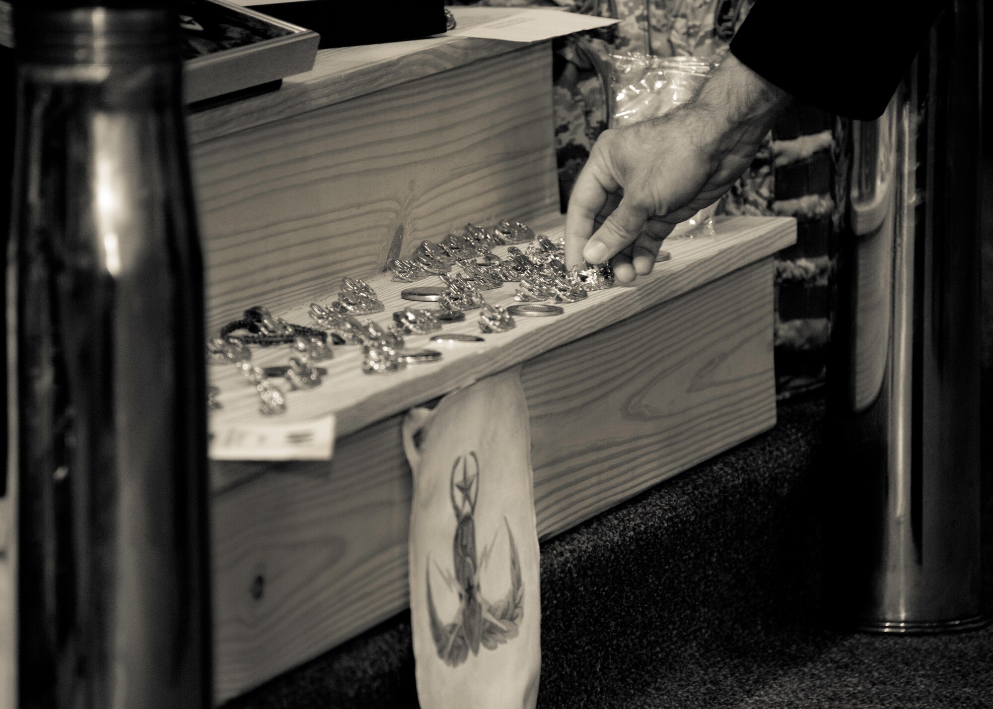Another explosive ordnance disposal badge is placed at the foot of the memorial display after the ceremony for Tech. Sgt. Daniel Douville at Eglin Air Force Base, July 14.  Douville, an EOD technician with the 96th CES, died June 26 as a result of injuries suffered from an improvised explosive device in Afghanistan.  Friends, family and the local community turned out to remember and praise his contributions to his country.  (U.S. Air Force photo/Samuel King Jr.)