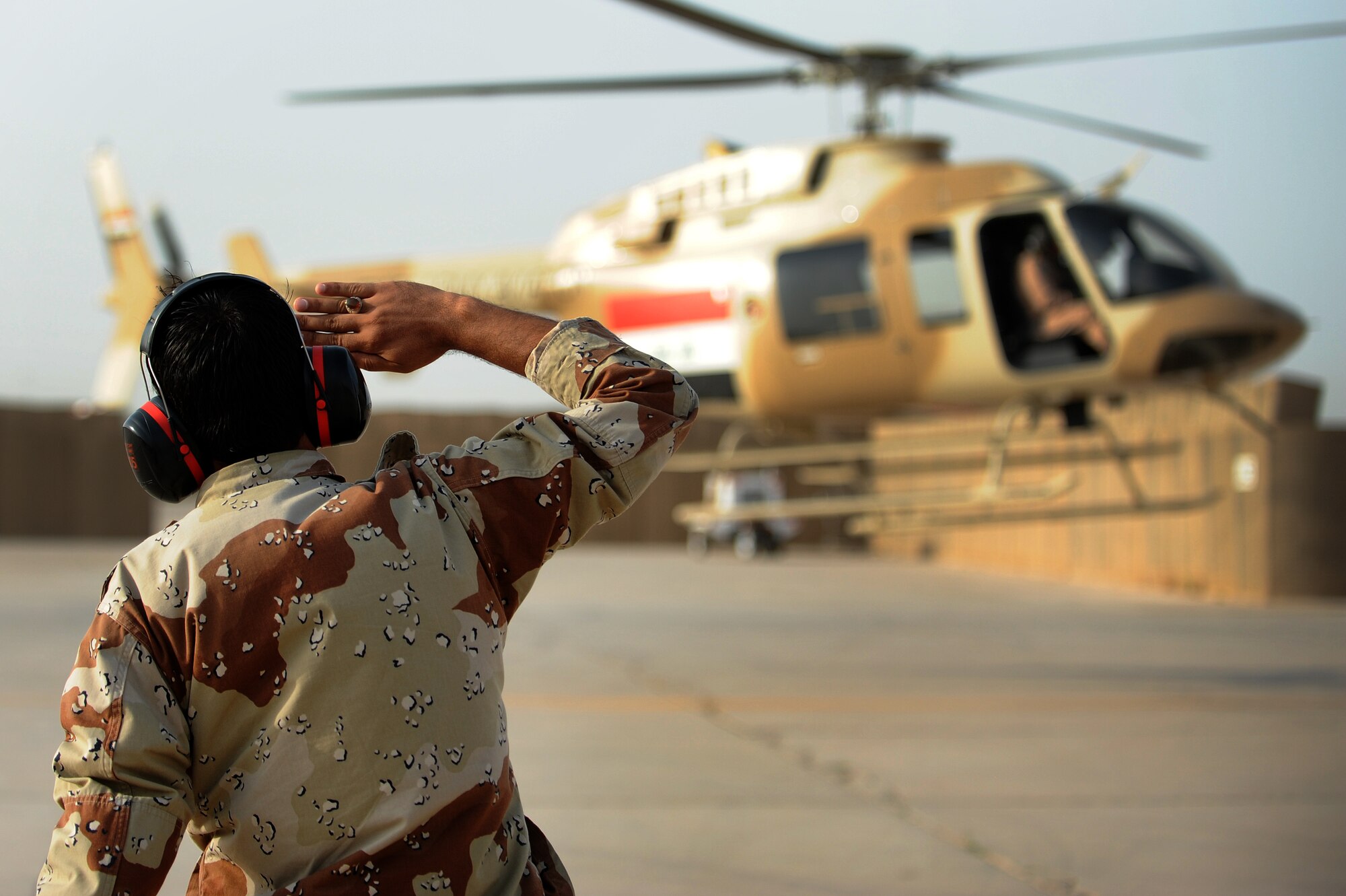An Iraqi Army Aviation Command, Squadron 21 ground crew member salutes a Bell 407 helicopter at takeoff, Taji Air Base, Iraq, July 12, 2011. Assigned at Taji Air Base, the 721st Air Expeditionary Advisory Squadron trains, advises and assists Iraqi pilots and maintenance personnel, focusing on sustainability, reliability and interoperability. (U.S. Air Force photo/Staff Sgt. Mike Meares)








