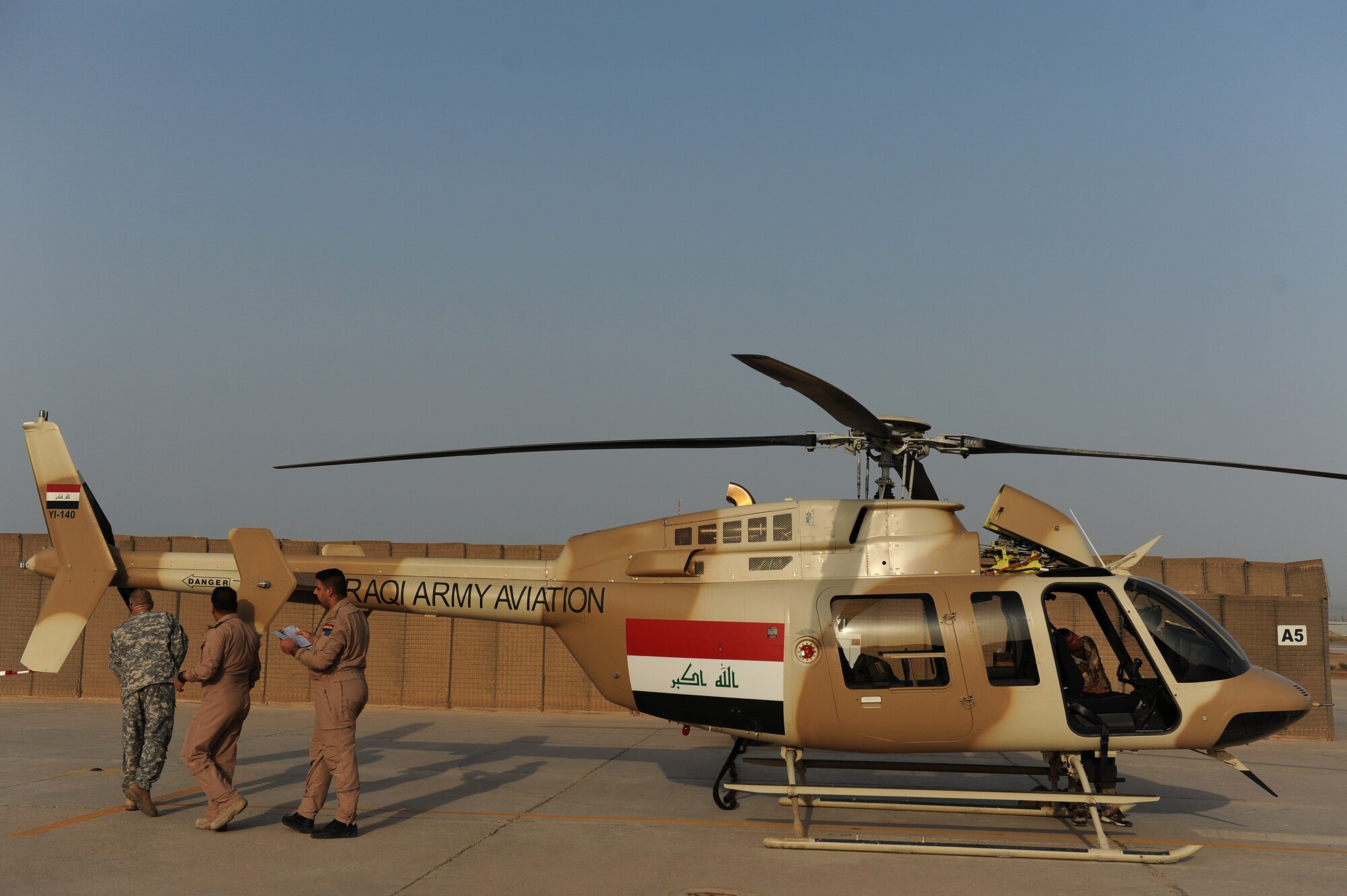 U.S. Army Maj. Kevin Ferner, 721st Air Expeditionary Advisory Squadron, and Bell 407 helicopter instructor pilot assists Iraqi Army Aviation Command, Squadron 21 pilots with a pre-flight inspection prior to their training flight, at Taji Air Base, Iraq, July 14, 2011. The 721st AEAS trains, advises and assists Iraqi pilots and maintenance personnel, focusing on sustainability, reliability and interoperability. (U.S. Air Force photo/Staff Sgt. Mike Meares)

