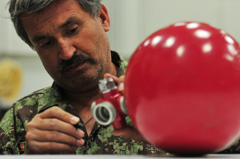 An Afghan Air Force maintainer performs an inspection on a fire suppression bottle in the maintenance hangar at the AAF compound in Kabul, Afghanistan. Each Mi-17 has two bottles installed on board in case of multiple fires. The inspection is performed over the threaded area to ensure there are no defects. Defects or cracks render the fire bottle unserviceable. Coalition advisers work daily at the AAF compound to instruct Afghan maintainers on the fine art of maintaining the Afghan Mi-17 and Mi-35 helicopters. (U.S. Air Force photo by Tech. Sgt. Brian E. Christiansen)  