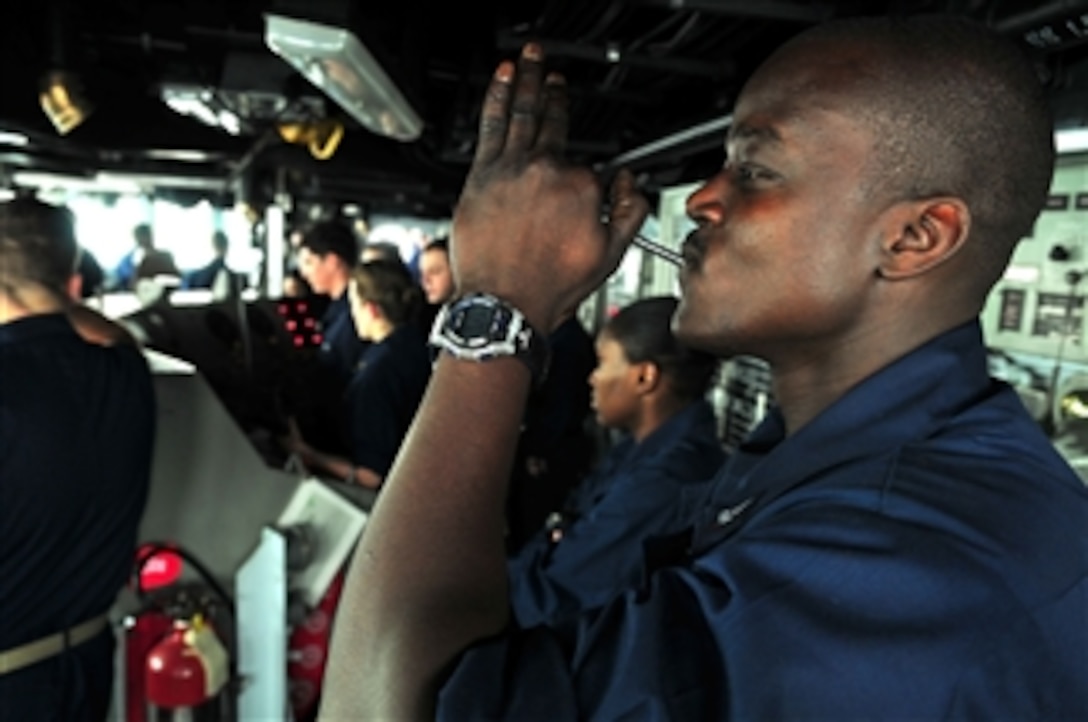 Petty Officer 3rd Class Alioune Wadji blows a boatswain's pipe over the ship's 1MC announcing system from the bridge of the amphibious assault ship USS Boxer (LHD 4) during a replenishment at sea in the Gulf of Aden on July 11, 2011.  The Boxer is underway supporting maritime security operations and theater security cooperation efforts in the U.S. 5th Fleet area of responsibility.  