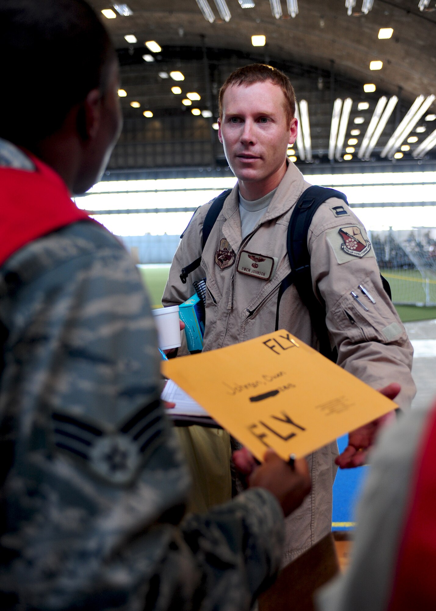 Capt. Owen Johnson, 34th Bomb Squadron B-1B Lancer pilot, receives his medical files from a 28th Medical Group Airman as he passes through a personnel deployment function line at Ellsworth Air Force Base, S.D., July 18, 2011. Approximately 300 Airmen processed through the line prior to deploying to Southwest Asia to support combatant commanders in the U.S. Central Command area of responsibility. (U.S. Air Force photo /Airman Alystria Maurer/Released)